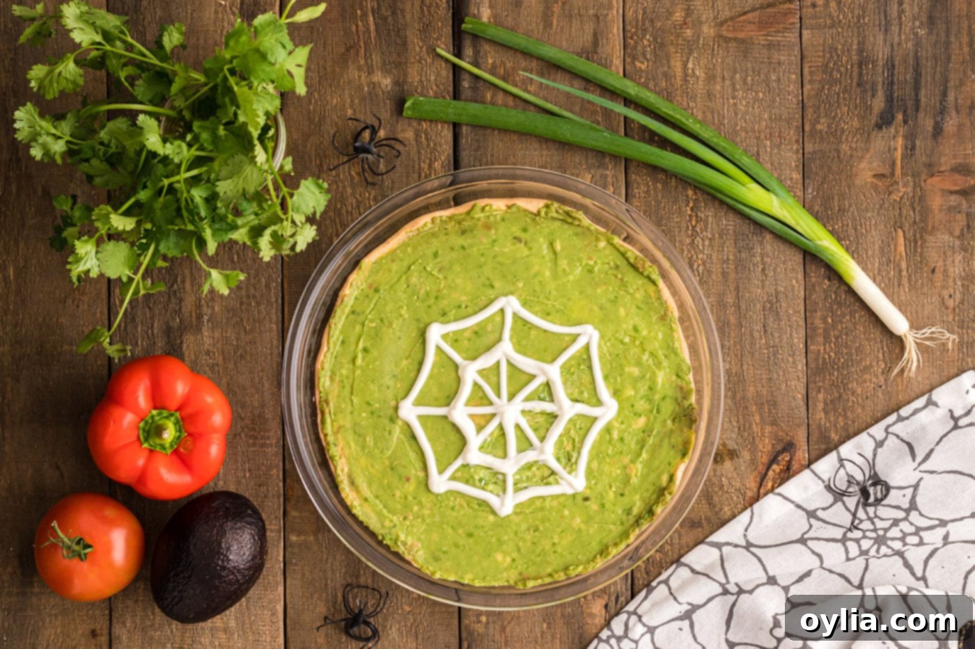 Finished sour cream spiderweb on the guacamole layer of the taco dip, ready for toppings