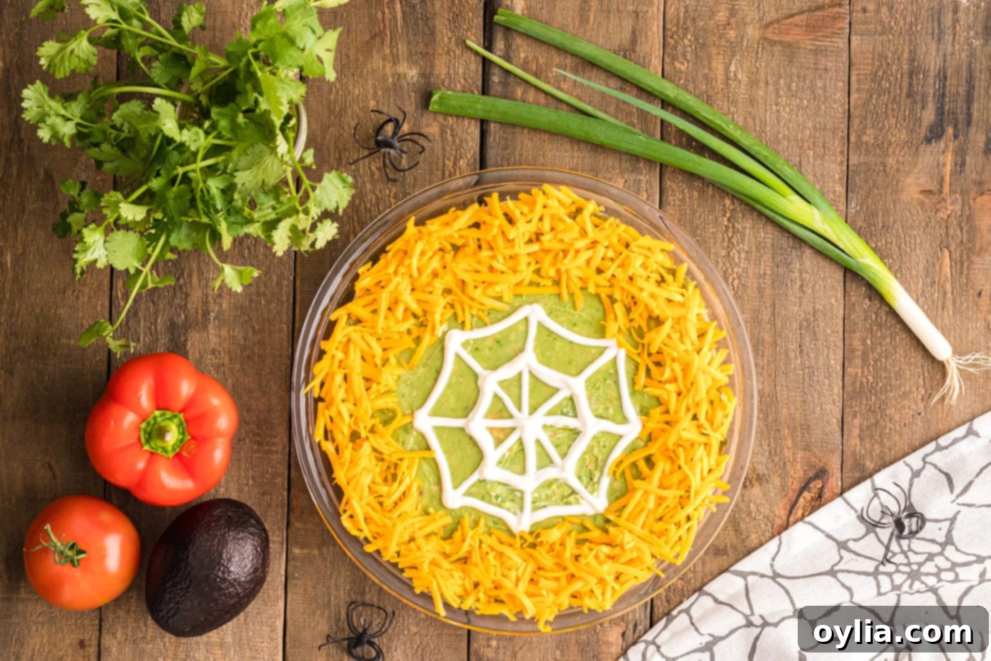 shredded cheddar cheese sprinkled around the edge of the taco dip, framing the spiderweb