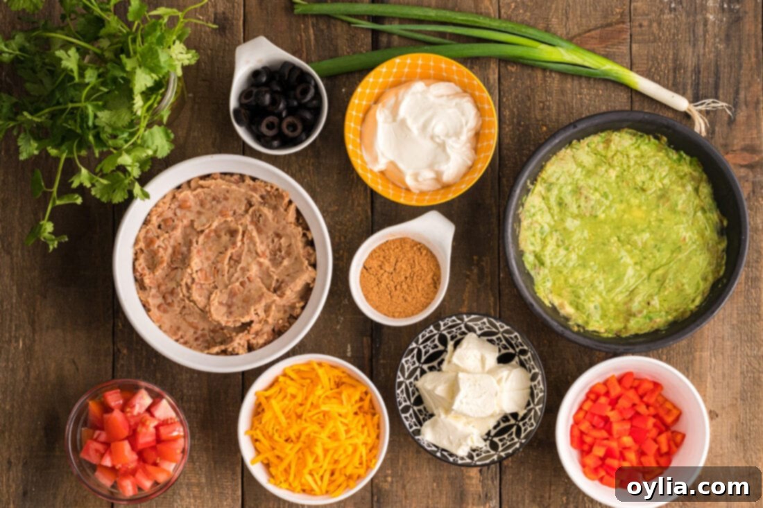 Array of fresh ingredients for Spider Web Taco Dip, including beans, sour cream, guacamole, and toppings