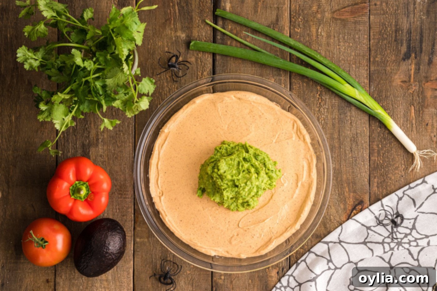 spreading green guacamole evenly over the sour cream taco dip layer