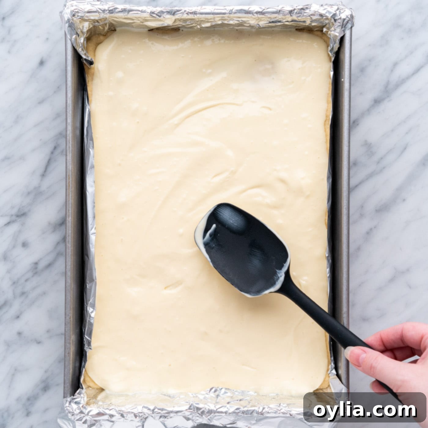 spreading cheesecake mixture over shortbread crust