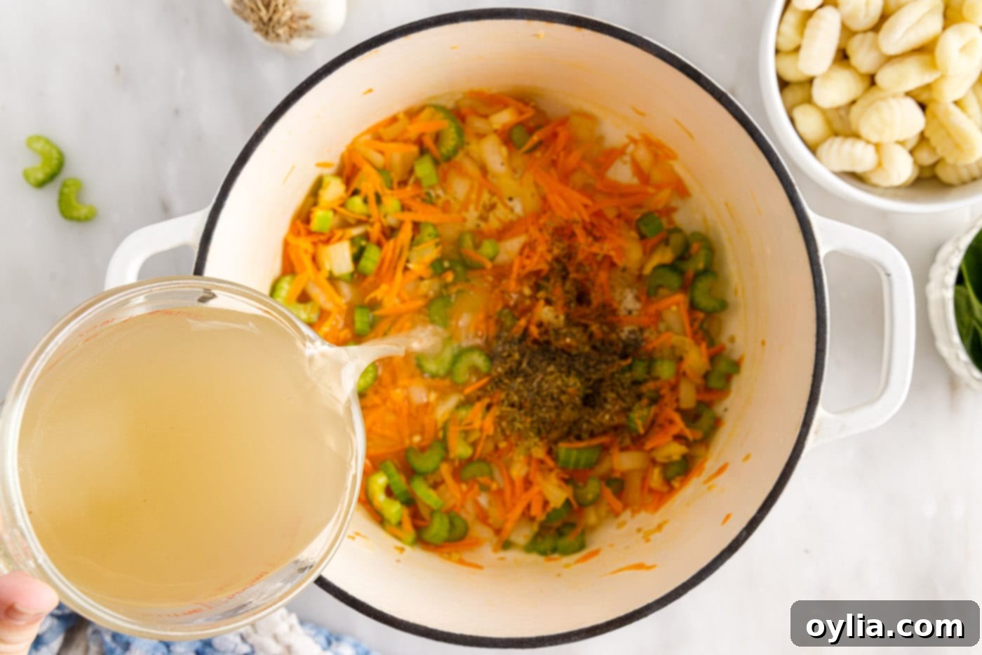 pouring broth over vegetables in a pot