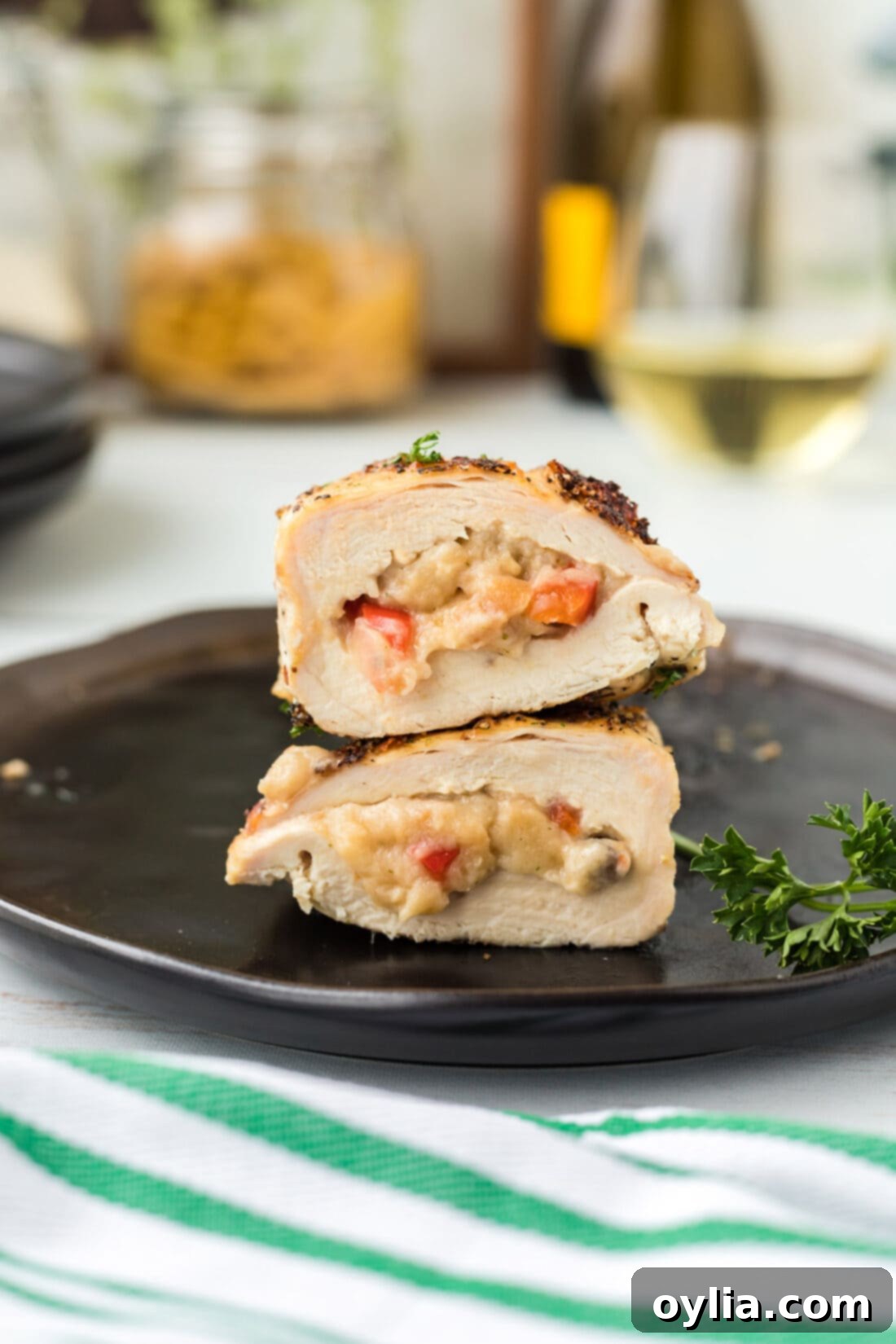 Stuffed Chicken Breast cut in half on plate, perfectly showcasing the moist chicken and rich filling, garnished with fresh herbs