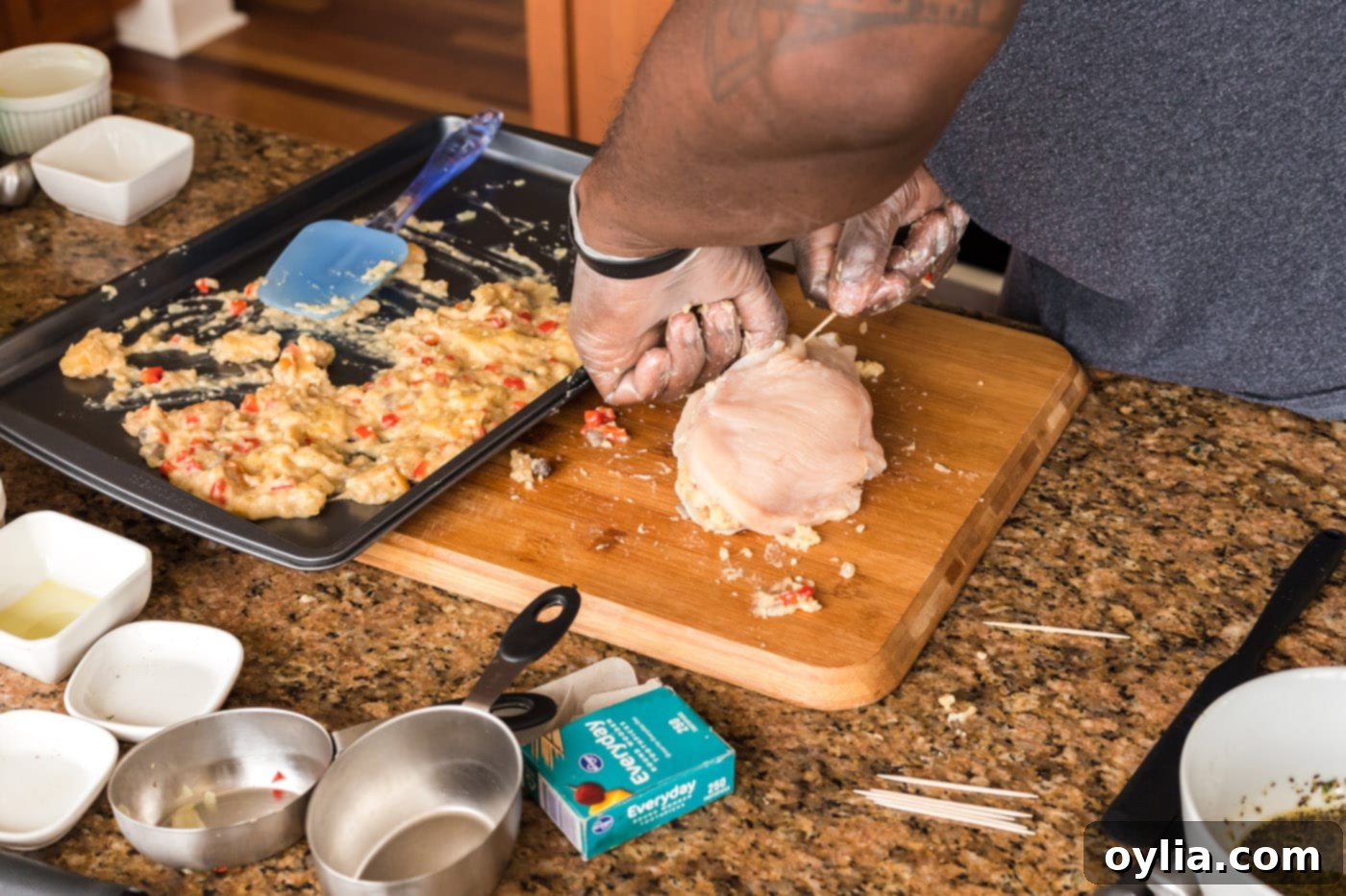 Securing a stuffed chicken breast closed with a toothpick to keep the filling intact during cooking