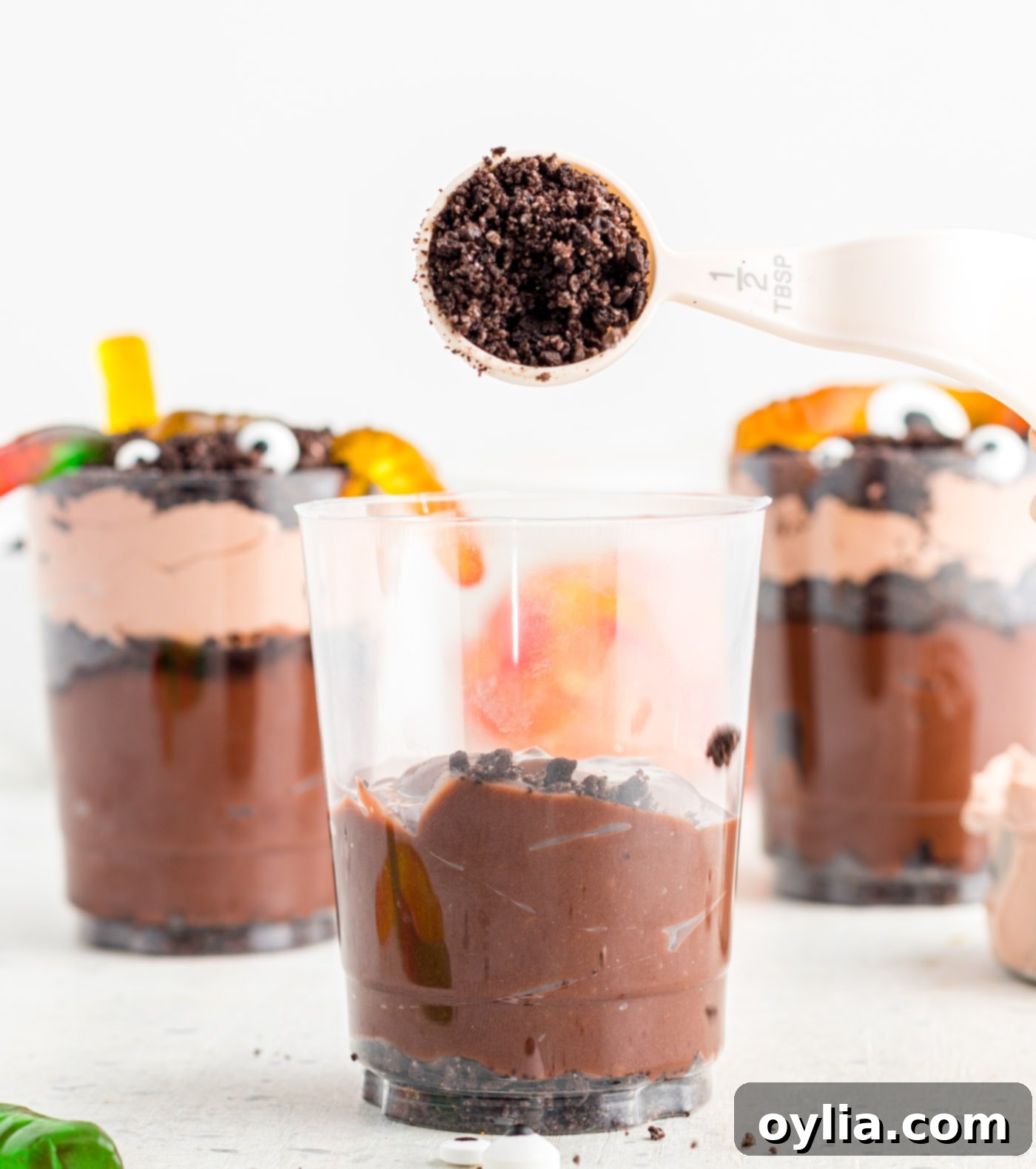 Adding a layer of crushed Oreo 'dirt' over the chocolate pudding in a dessert cup.