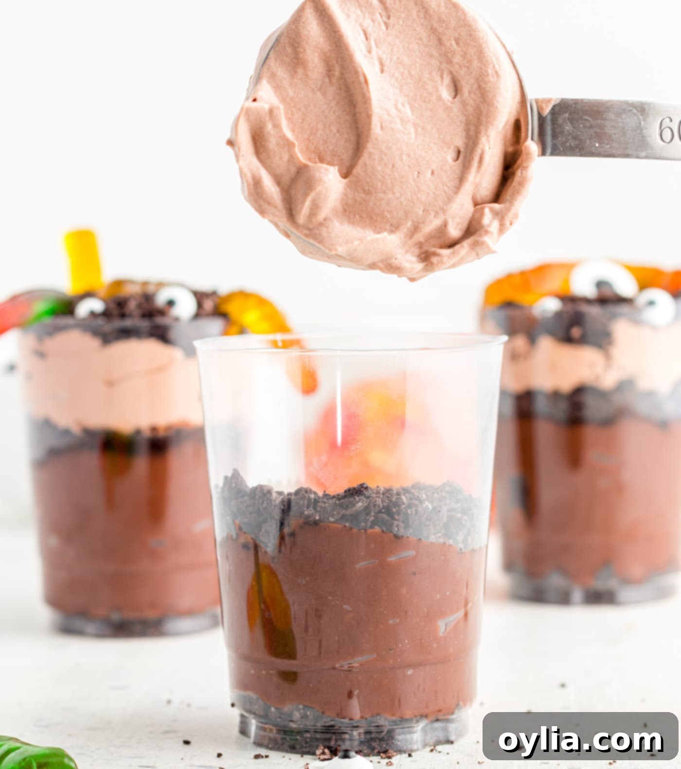 A layer of whipped chocolate pudding and Cool Whip over crushed Oreo cookies in a clear cup.