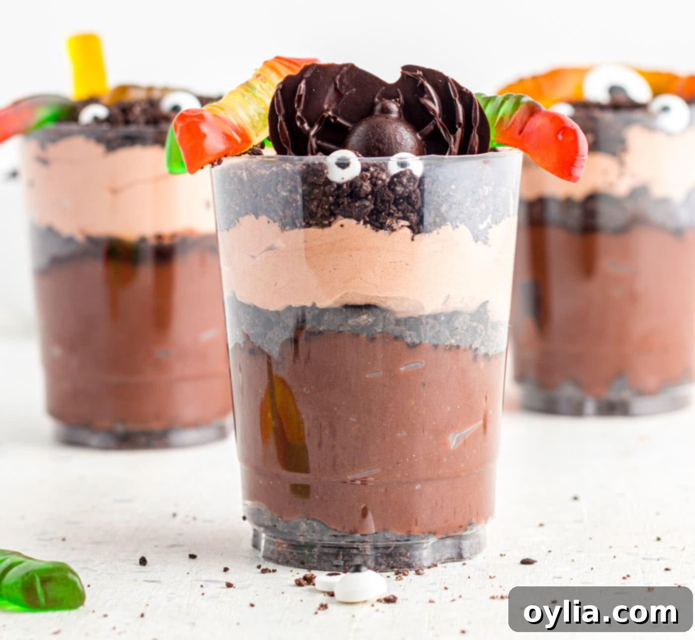Finished Halloween Dirt Cups decorated with gummy worms and candy eyeballs, ready to serve.