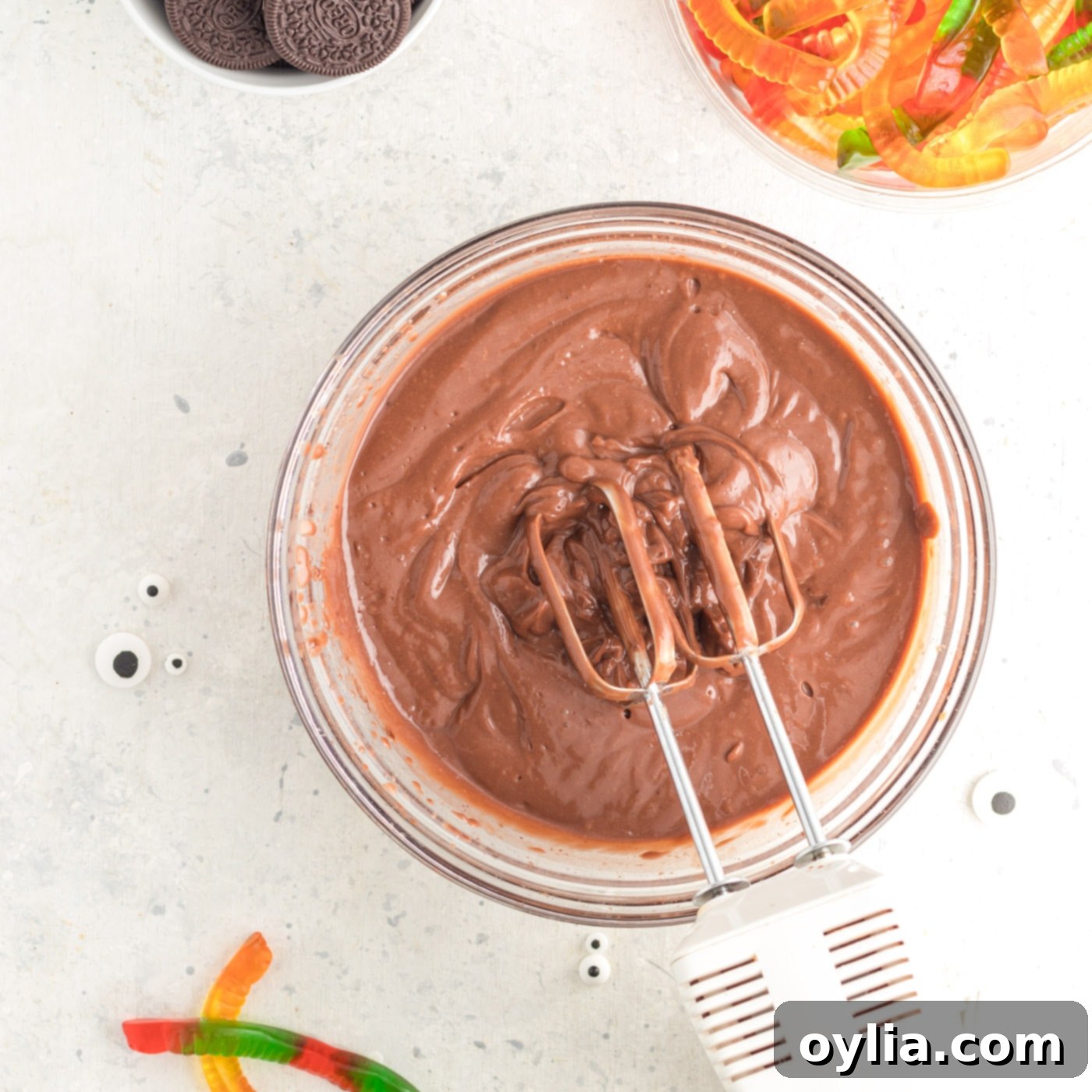 Electric mixer blending chocolate pudding in a bowl.