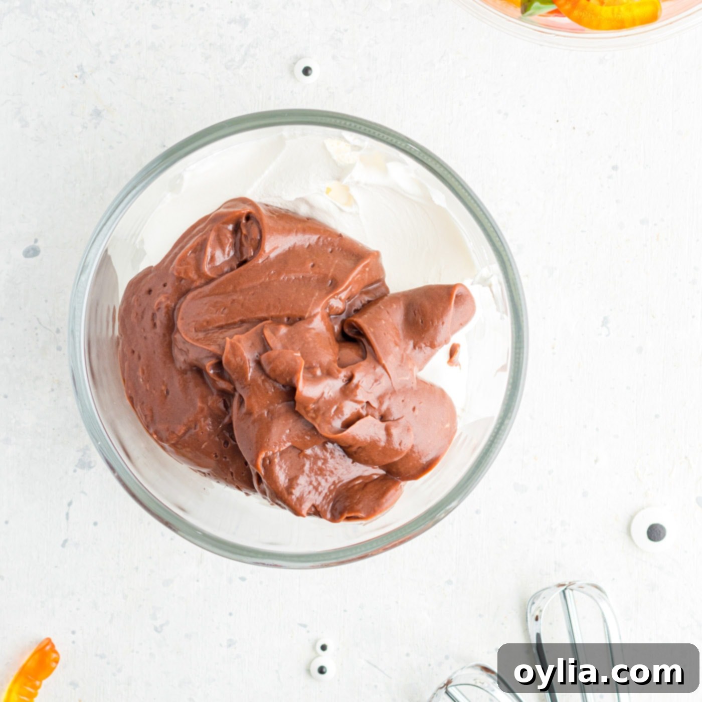 Cool Whip and a scoop of chocolate pudding in a mixing bowl.