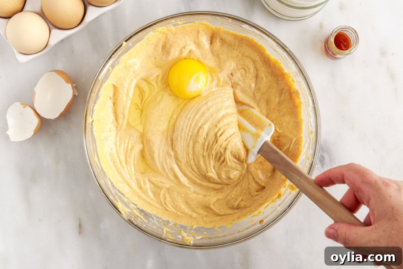 Eggs being gently mixed into the pumpkin cheesecake filling.