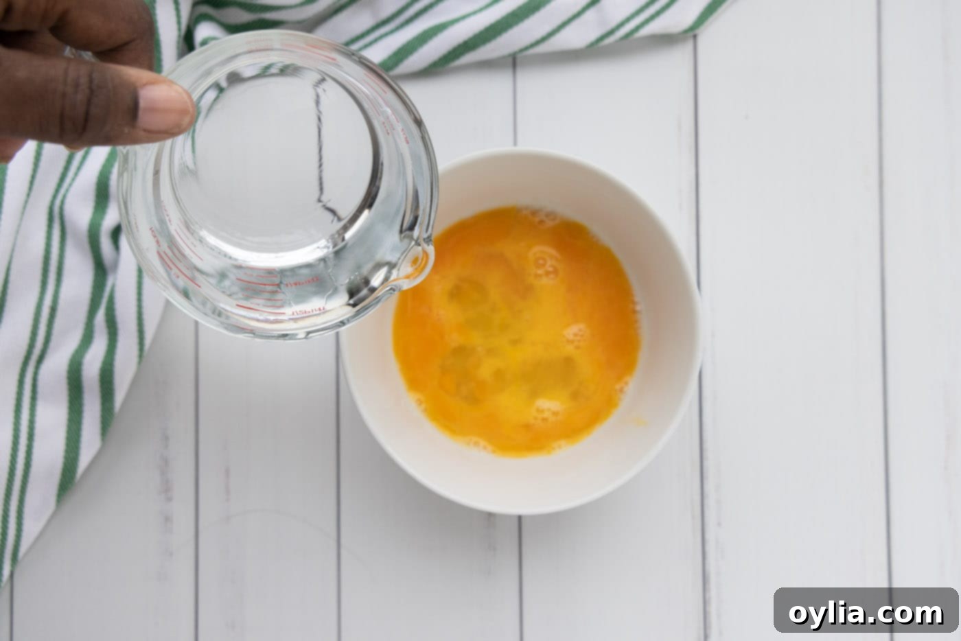 pouring water into eggs in a bowl