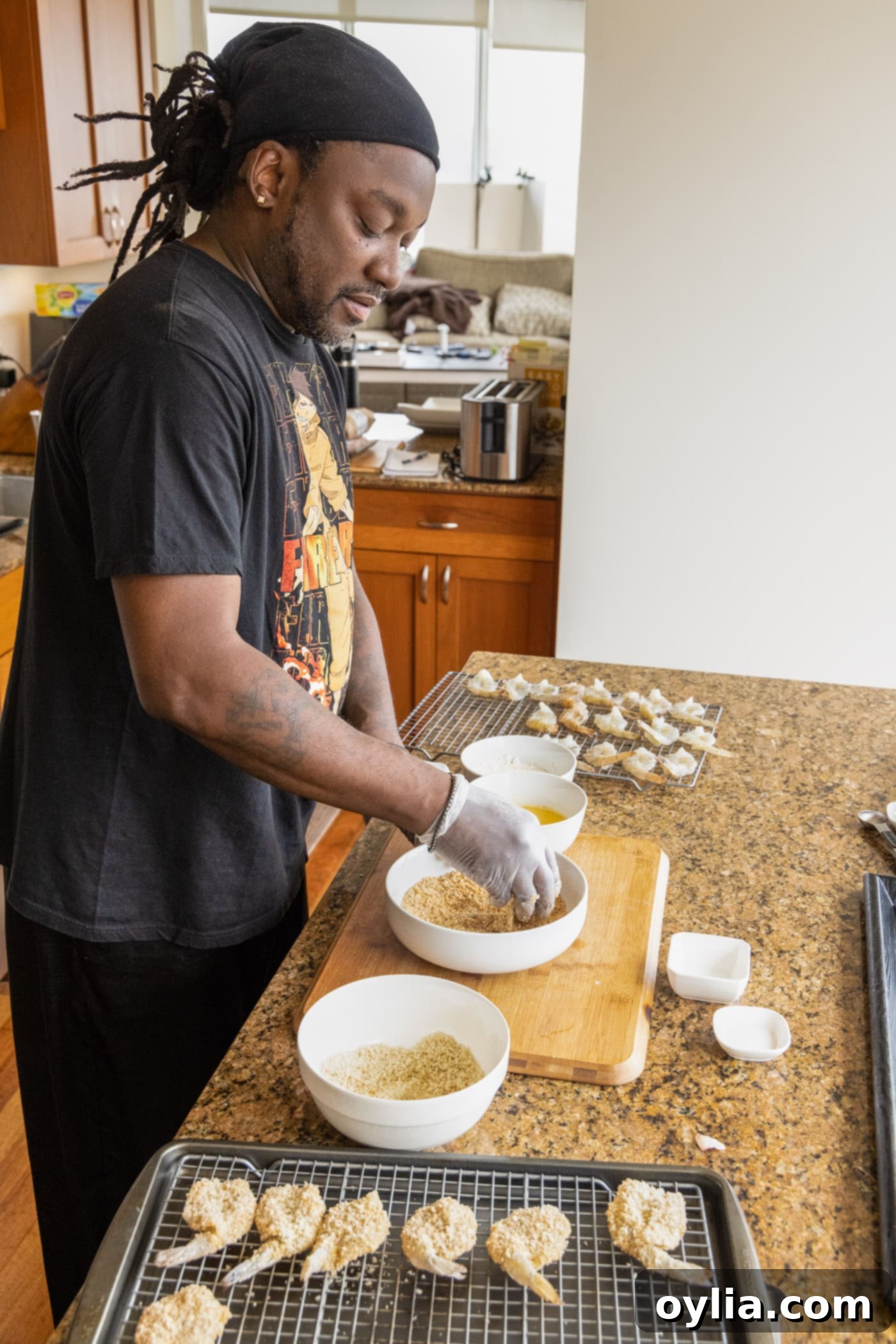 man dredging shrimp in breadcrumbs and eggs