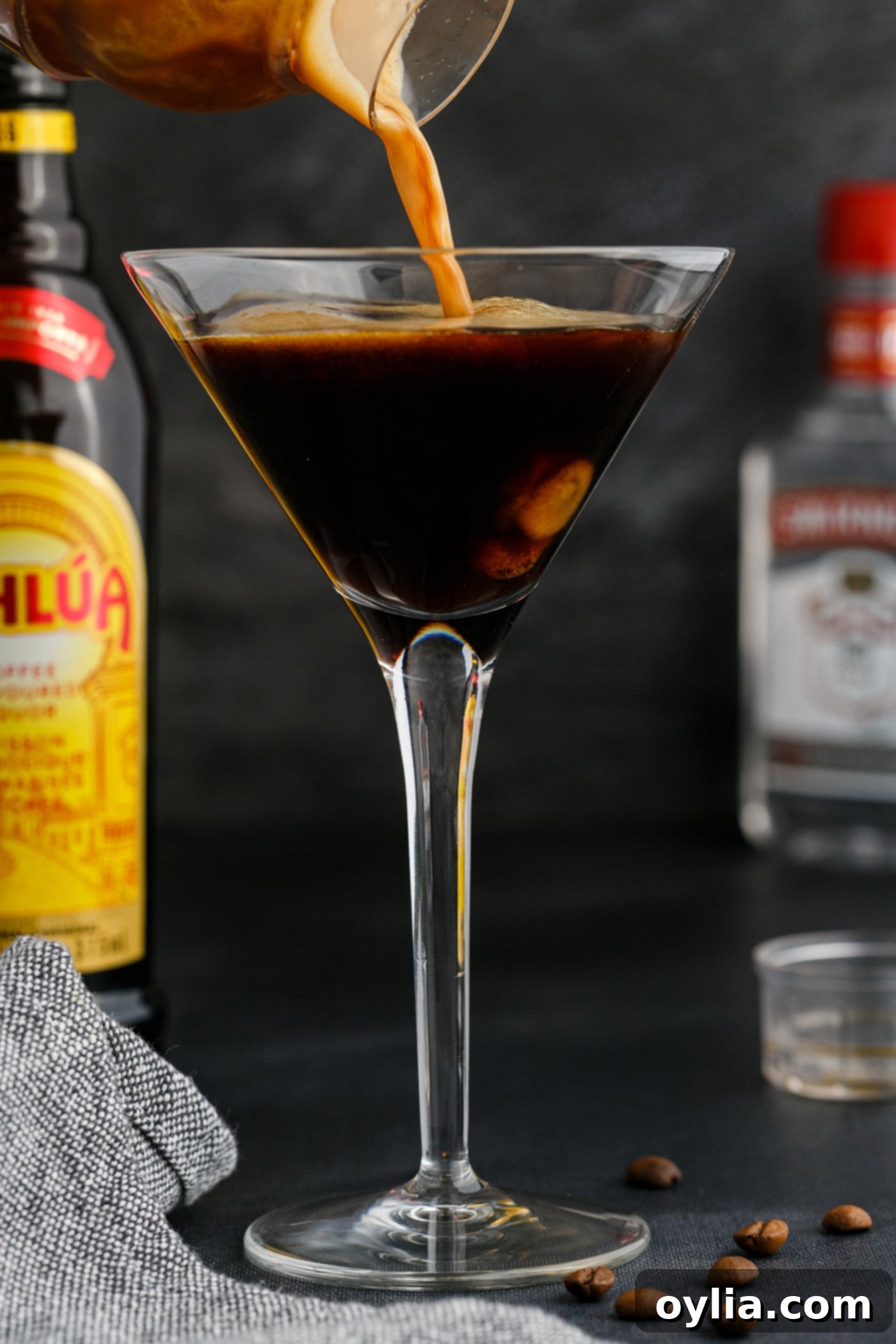 Skillfully straining a freshly shaken Espresso Martini into an elegant martini glass, showcasing the frothy layer forming at the top.