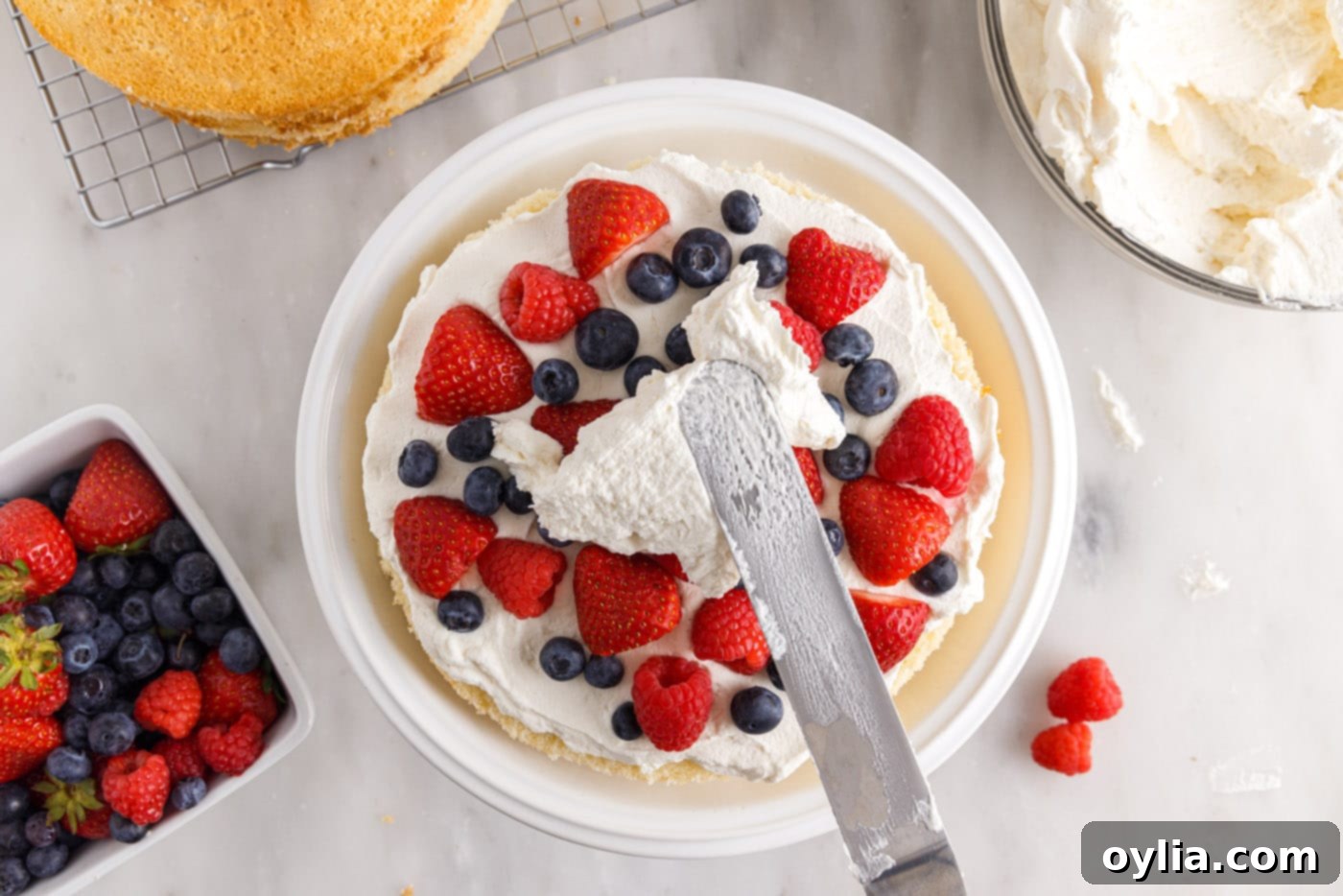 spreading chantilly frosting on top of fresh berries