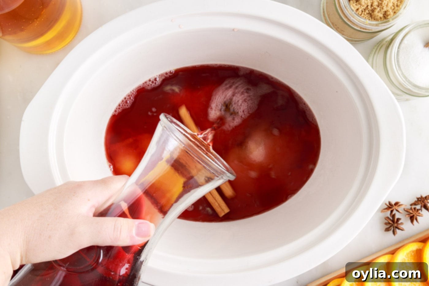 pouring juices into hot cranberry punch in the crockpot