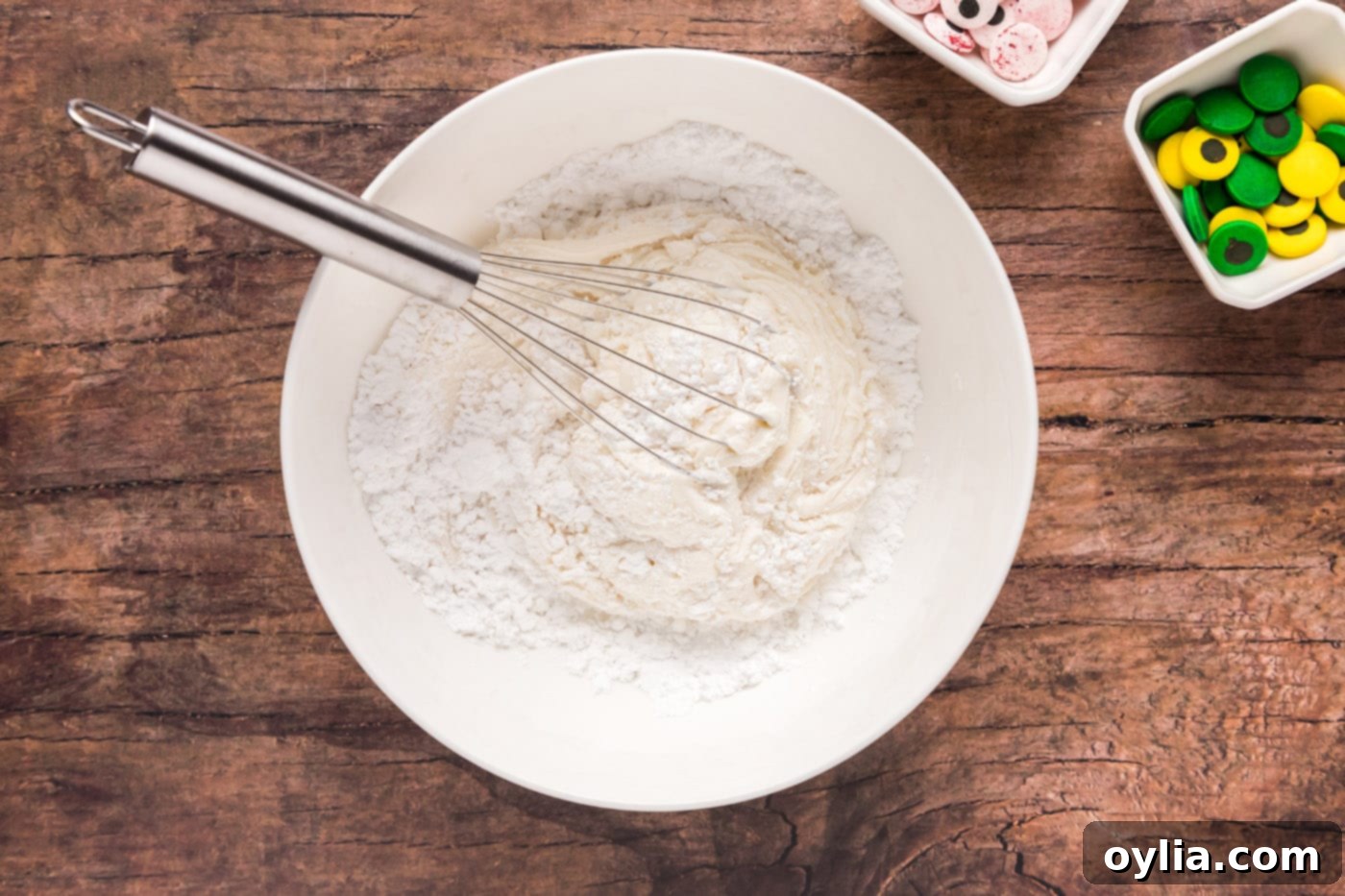 Whisking powdered sugar with vanilla frosting for mummy cookies
