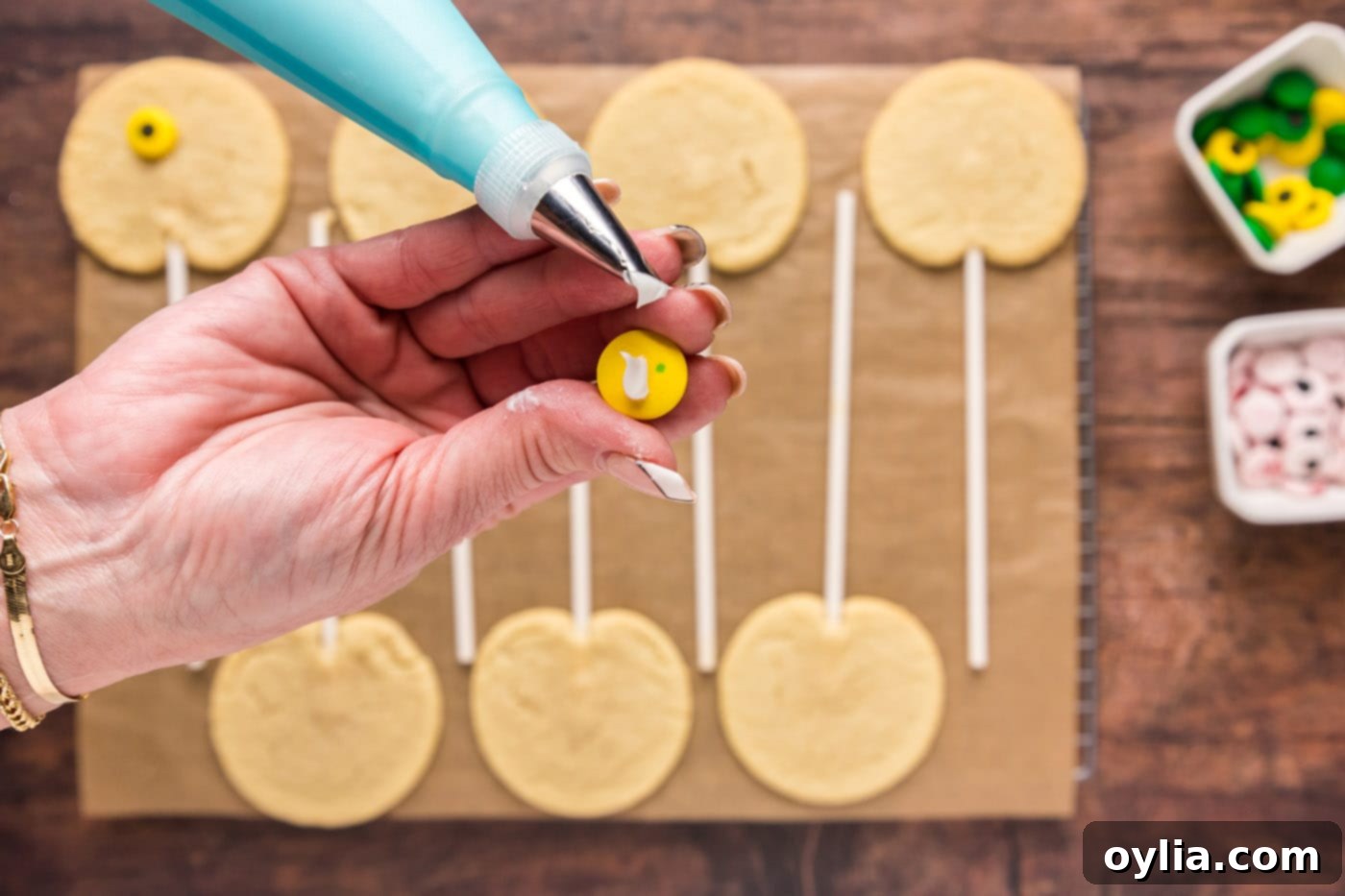Adding frosting to the back of a candy eyeball before placing on the cookie