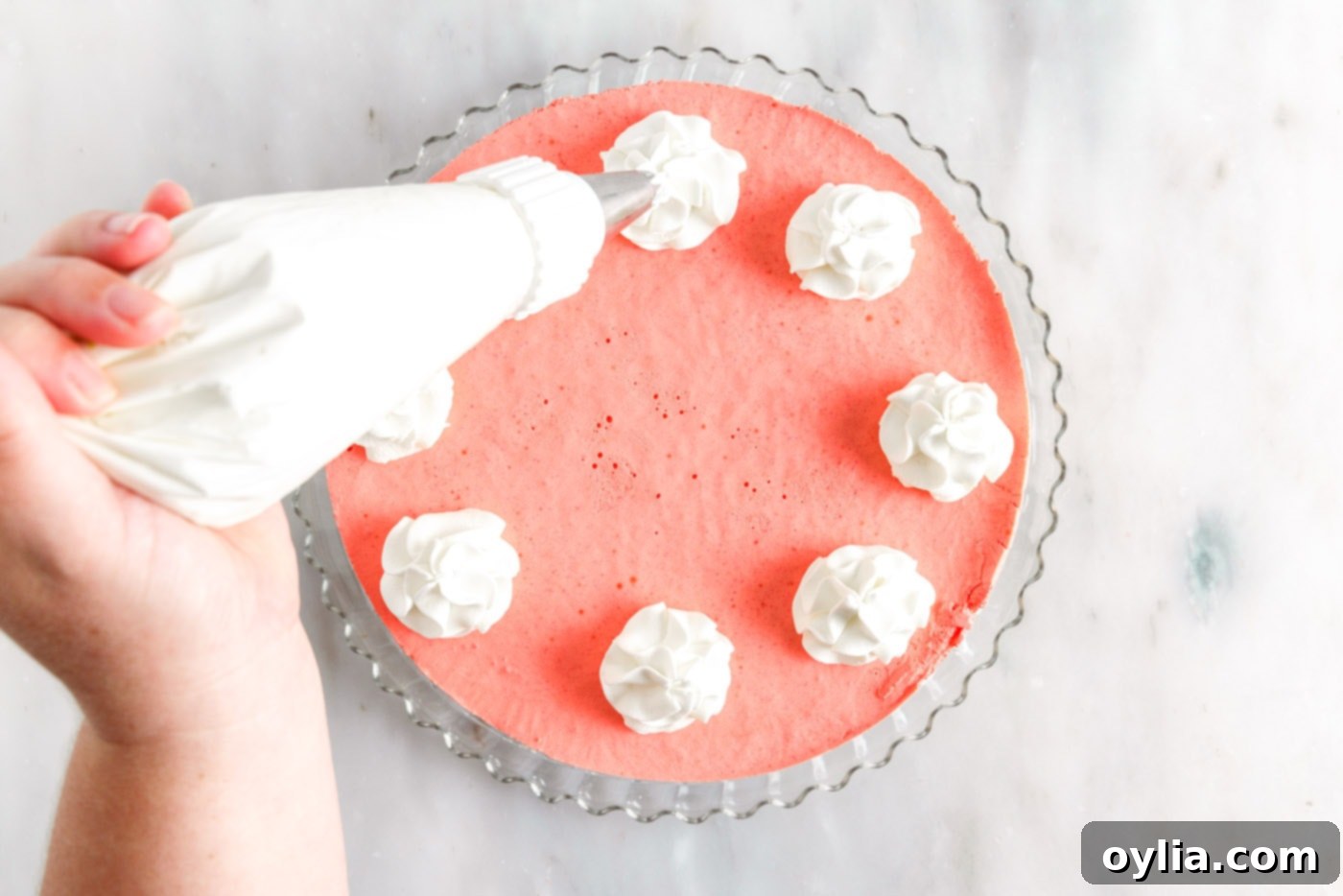 piping whipped cream on top of layered jello pie