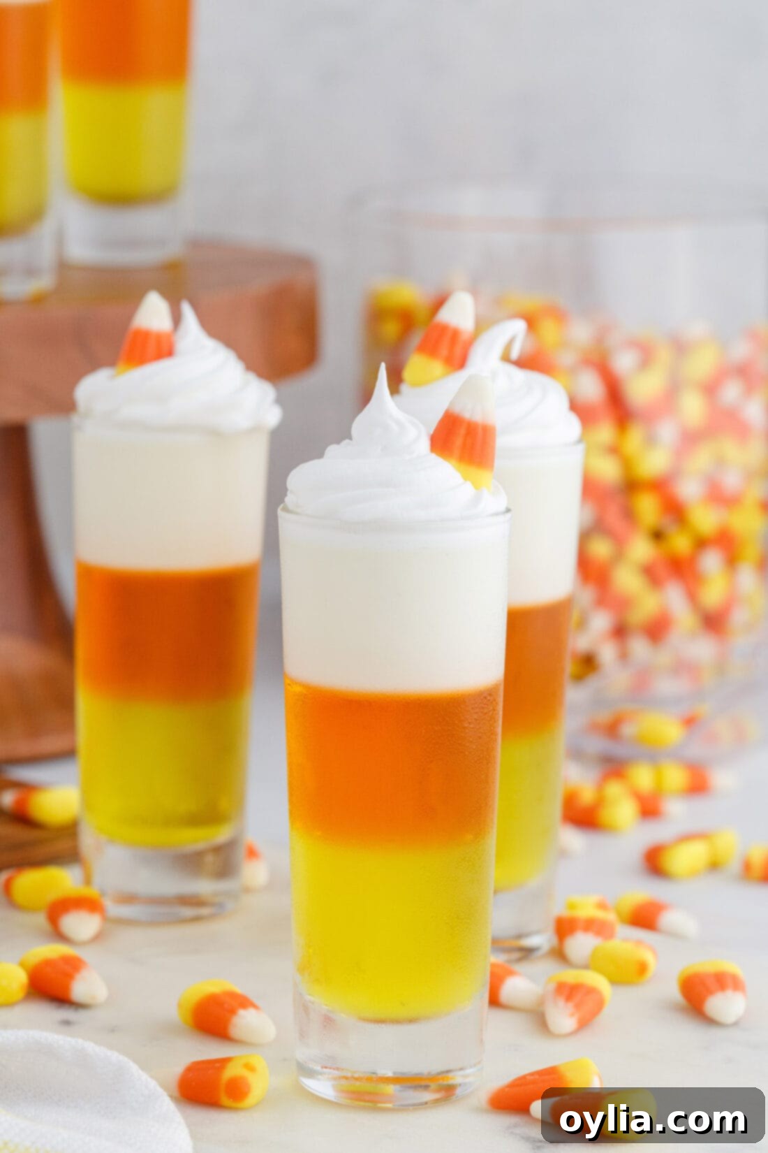 Candy Corn Jello Shots arranged with candy corn in the background for a Halloween display