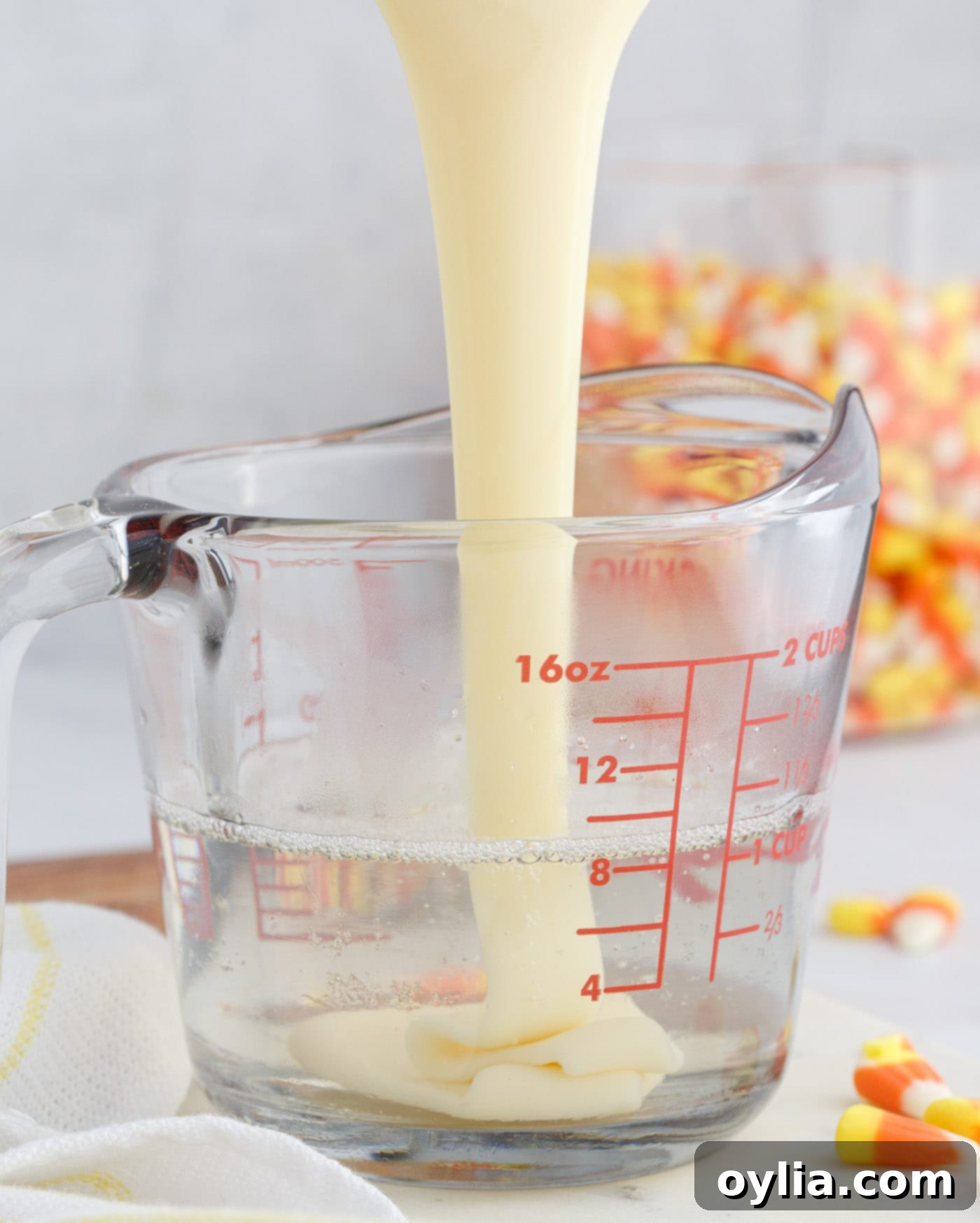 Pouring sweetened condensed milk into unflavored gelatin and vodka mixture