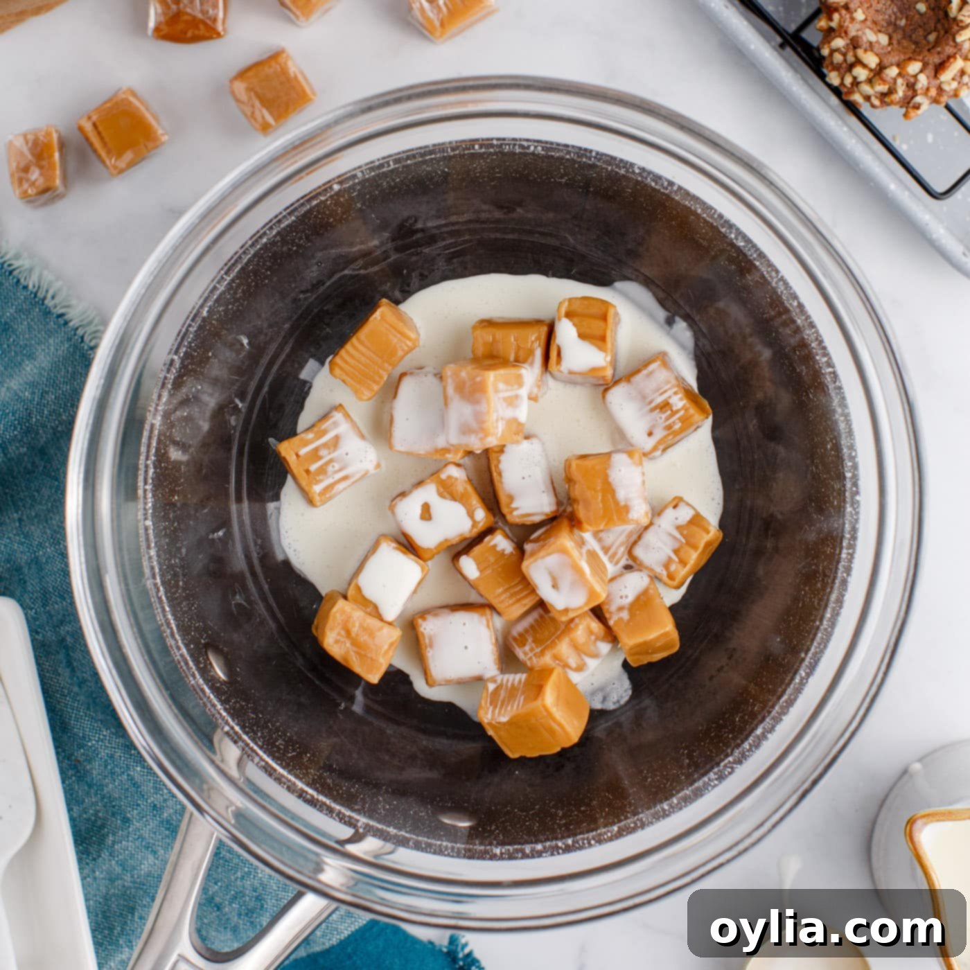 Kraft caramels and heavy cream melting in a heat-safe bowl over a saucepan using a double-boiler method.