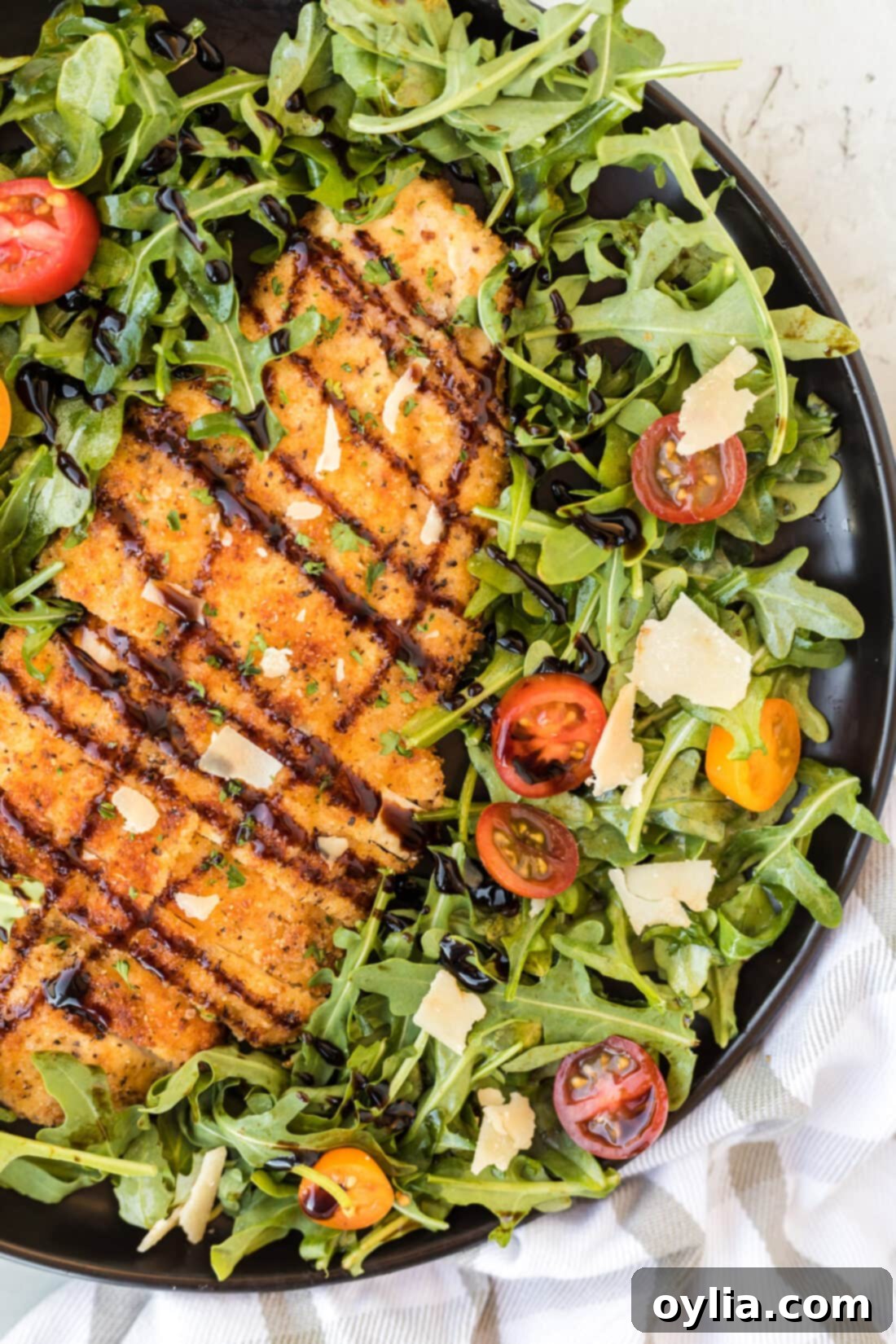 Two golden, crispy Chicken Milanese cutlets served on a plate with fresh mixed green salad, ready to be enjoyed.