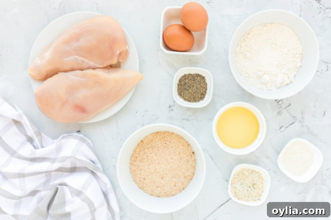 A flat lay photograph showcasing all the ingredients required for Chicken Milanese, including chicken breasts, breadcrumbs, flour, eggs, olive oil, and various spices.