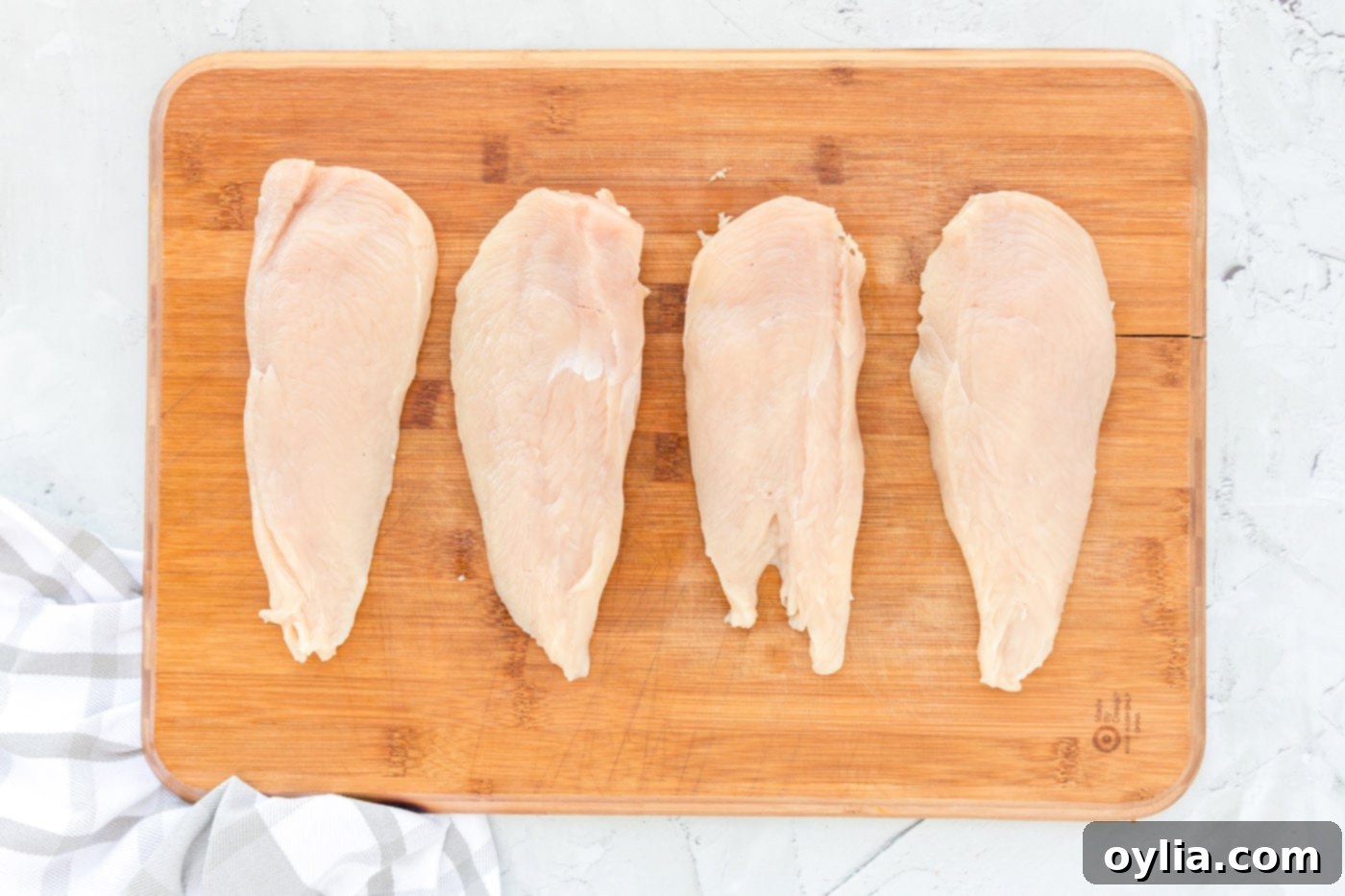 Showing how to butterfly a chicken breast on a cutting board to create thinner cutlets for Chicken Milanese.
