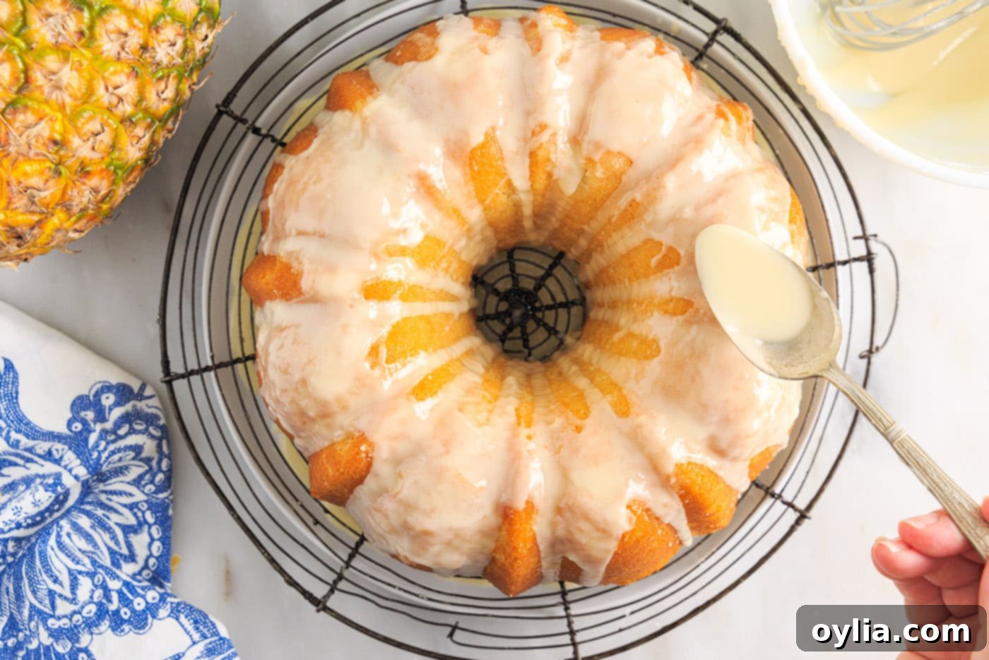 Spoonful of pineapple glaze being drizzled over a pineapple pound cake