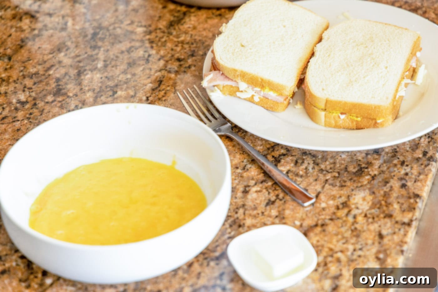 whisked eggs in a bowl and monte cristo sandwich on the side