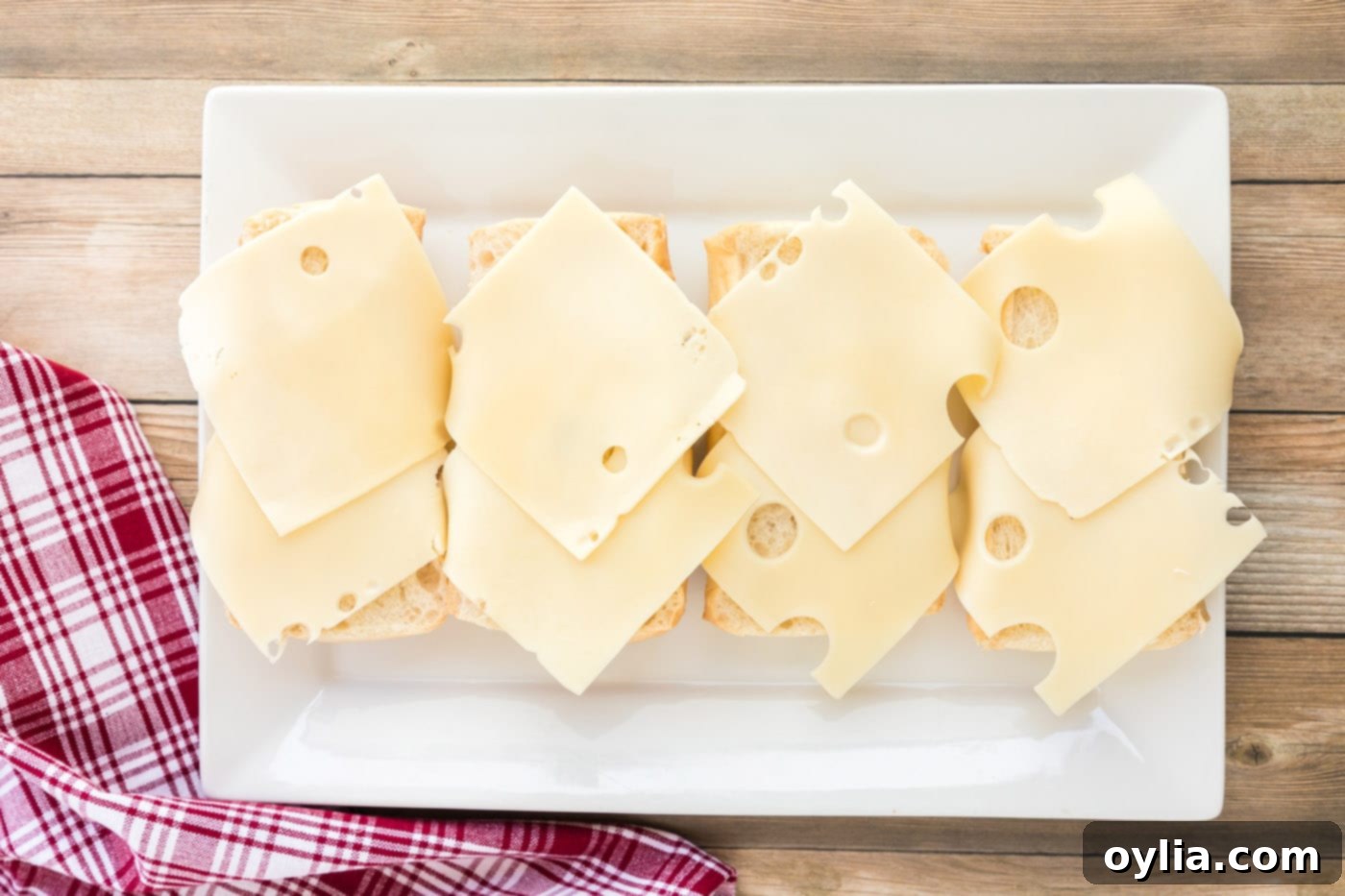 Swiss cheese layered on Cuban bread, forming the base of the sandwich