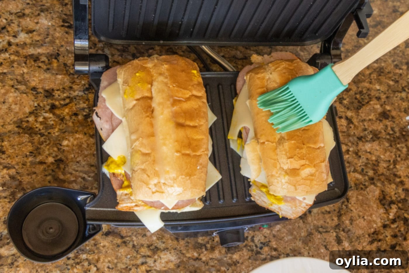 Brushing melted butter on the top of the Cuban sandwich before pressing