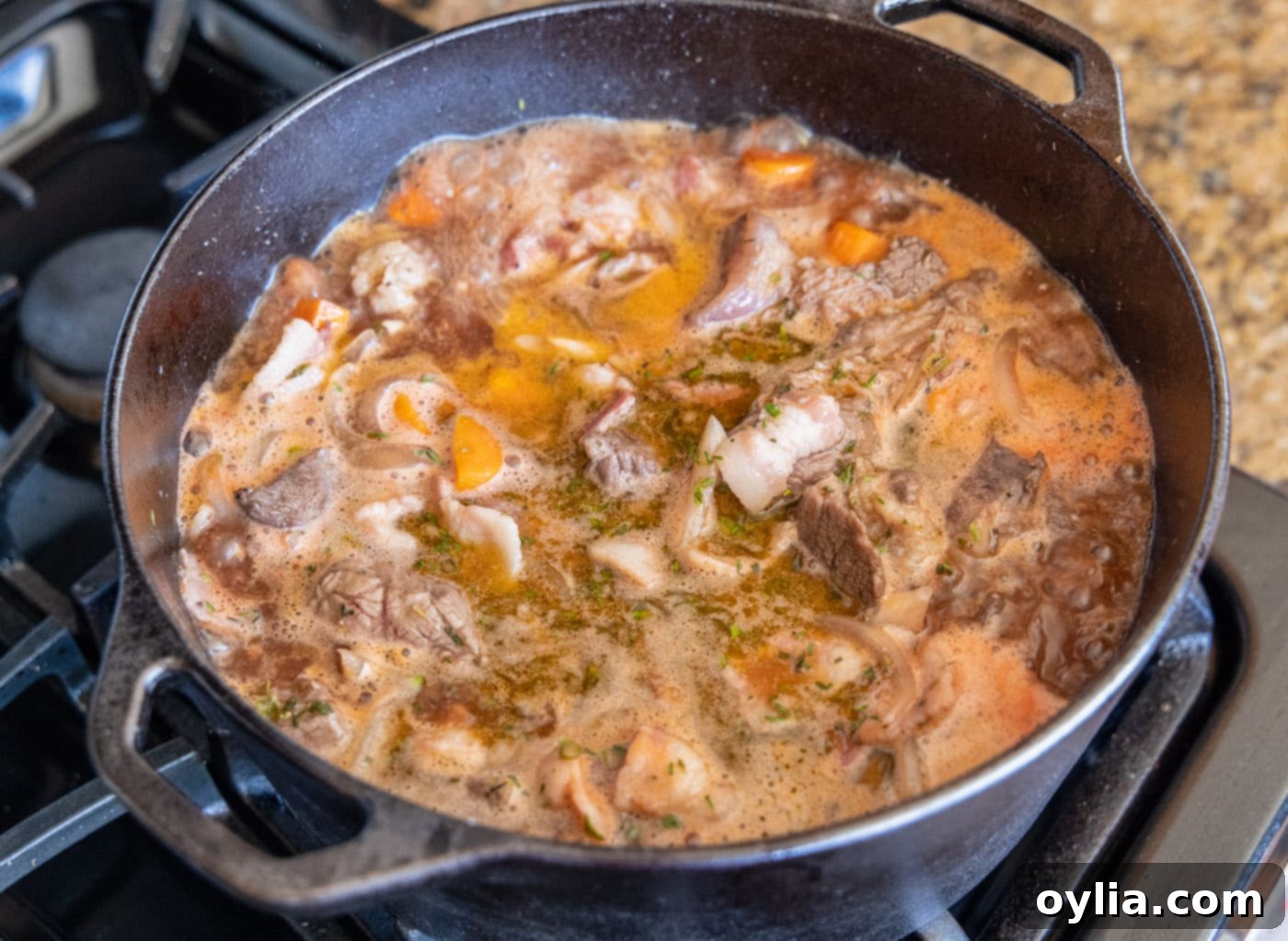 Beef Bourguignon simmering in a Dutch oven before going into the oven for braising