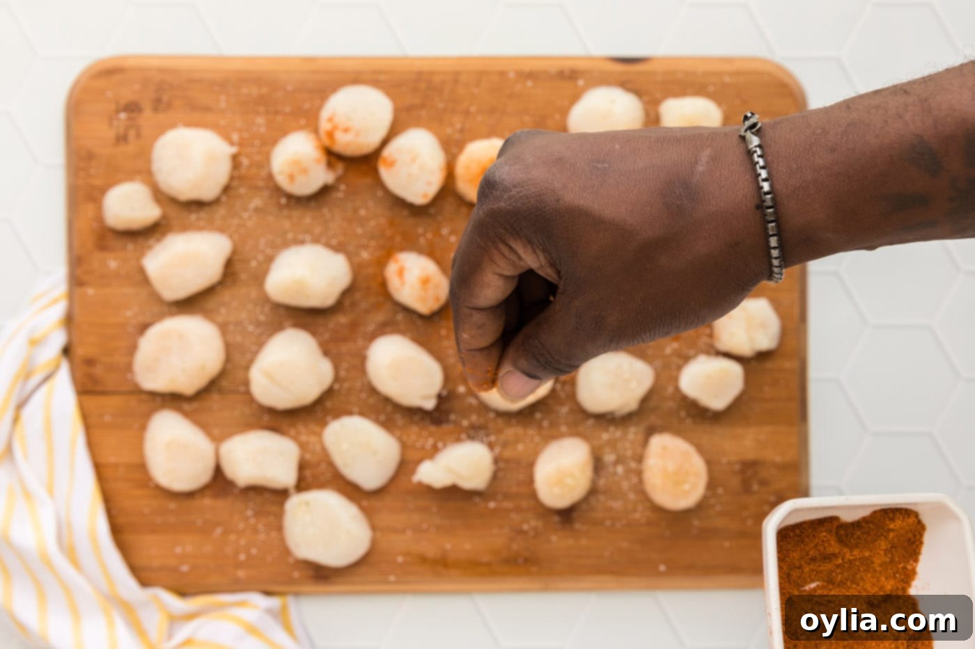 Crispy Air-Fried Scallops 5 Seasoning raw scallops with Old Bay and garlic salt on a cutting board