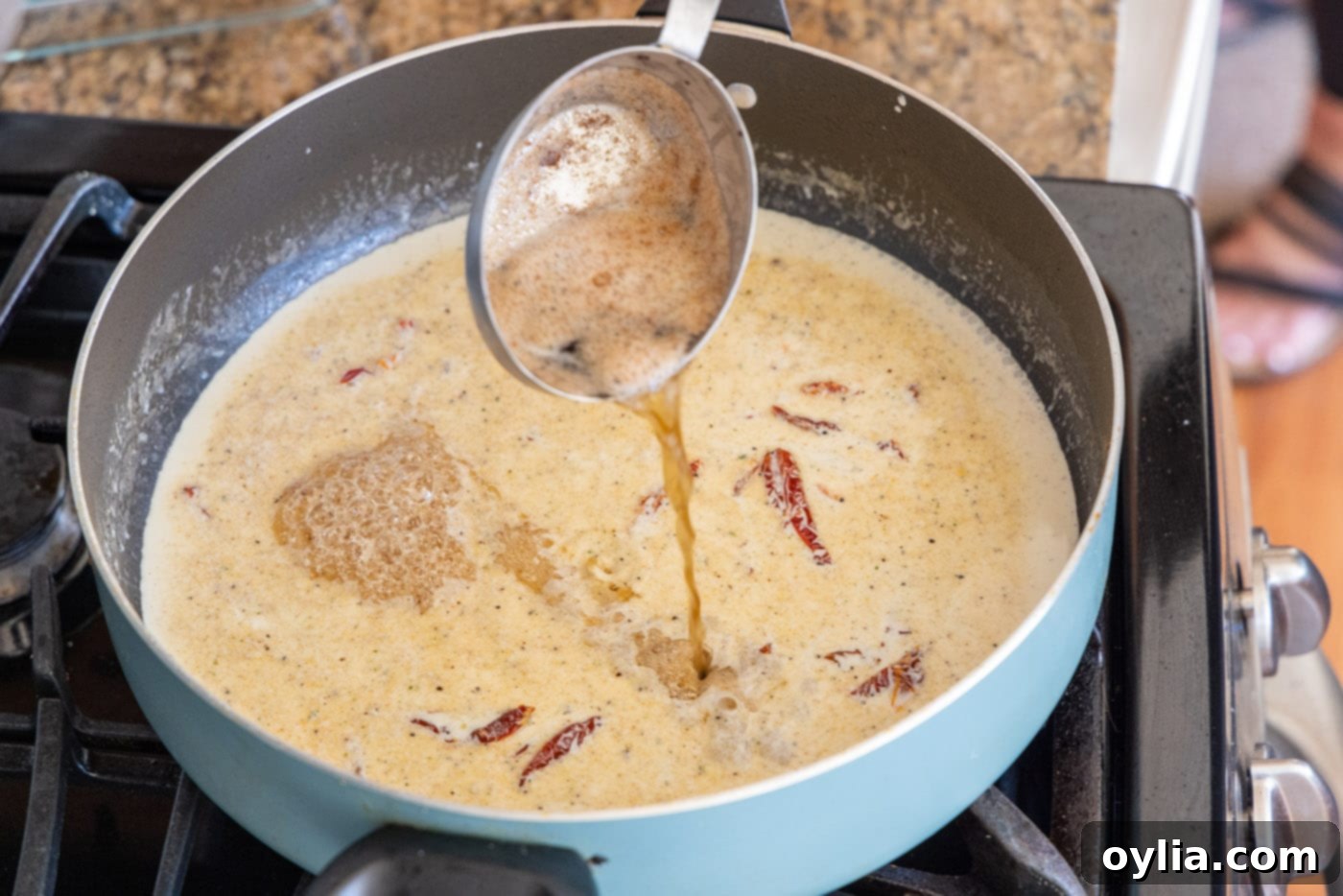 Adding reserved butter and oil drippings back into the heavy cream sauce in a skillet
