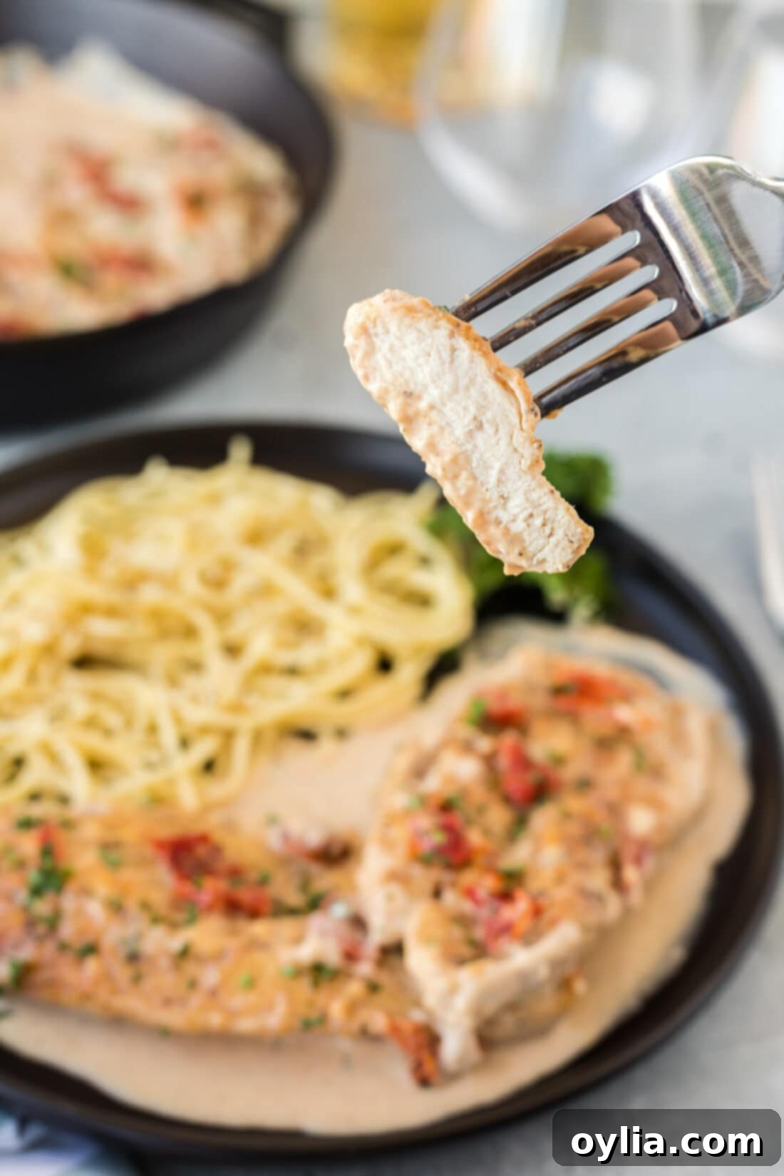 A forkful of Marry Me Chicken showing tender chicken and creamy sauce with sun-dried tomatoes