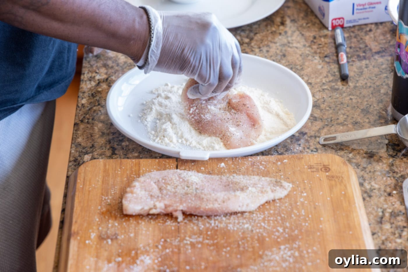 Dredging chicken cutlets in a bowl of all-purpose flour