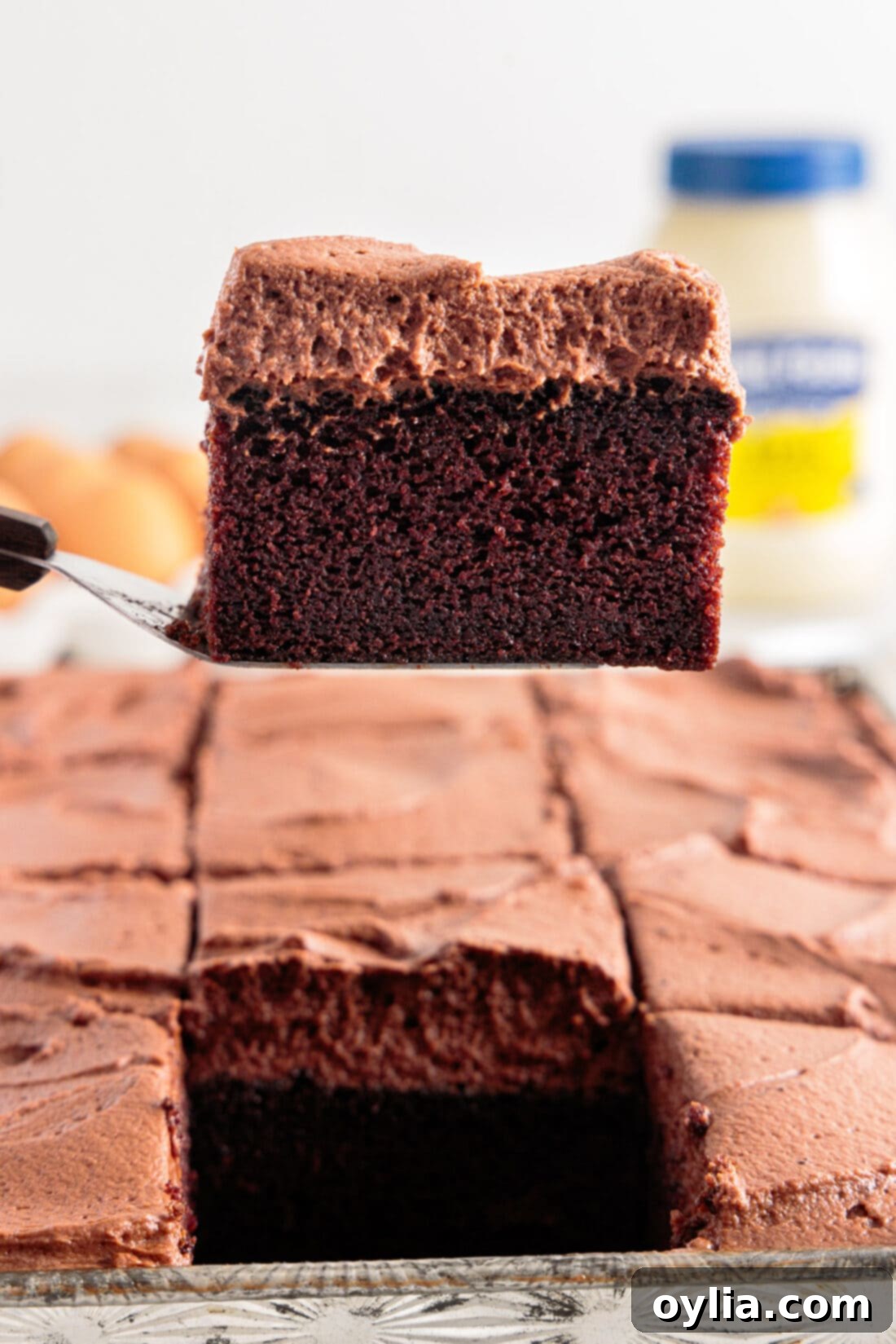 Moist Mayonnaise Cake 2 Spatula lifting a generous slice of moist Chocolate Mayonnaise Cake with rich frosting