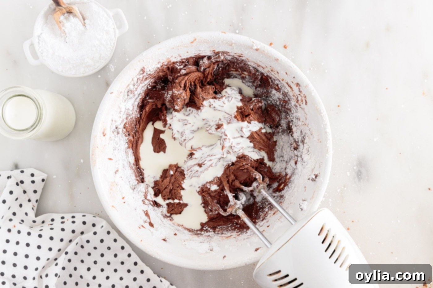 hand mixer incorporating chocolate frosting ingredients into a smooth mixture
