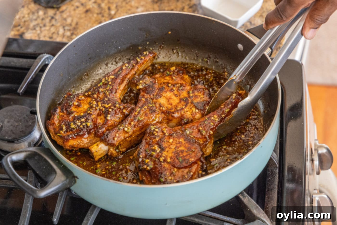 flipping veal chops in a skillet with tongs