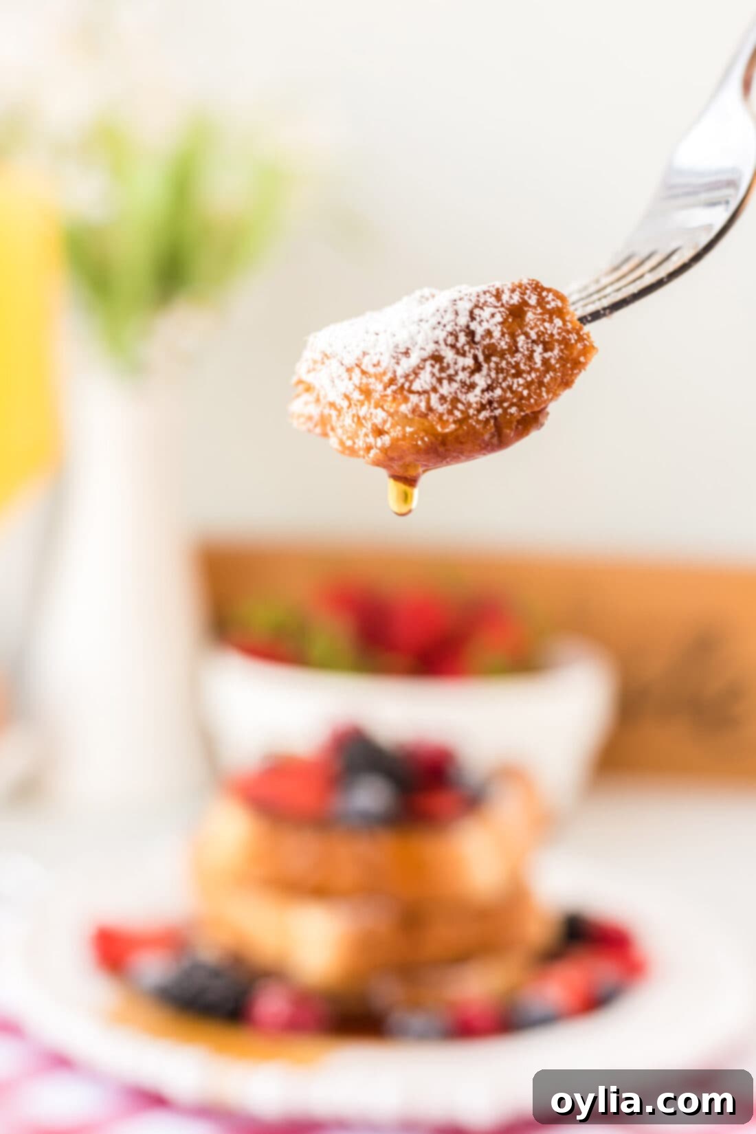 A fork piercing a piece of golden-brown French Toast with a soft, fluffy interior