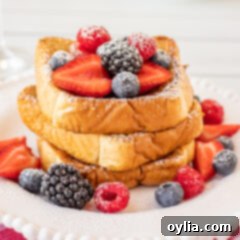 French Toast on a plate with berries and powdered sugar