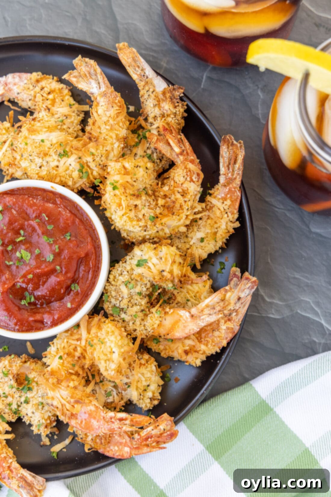Crispy Air Fryer Coconut Shrimp served on a plate with a side of dipping sauce, garnished with fresh herbs.