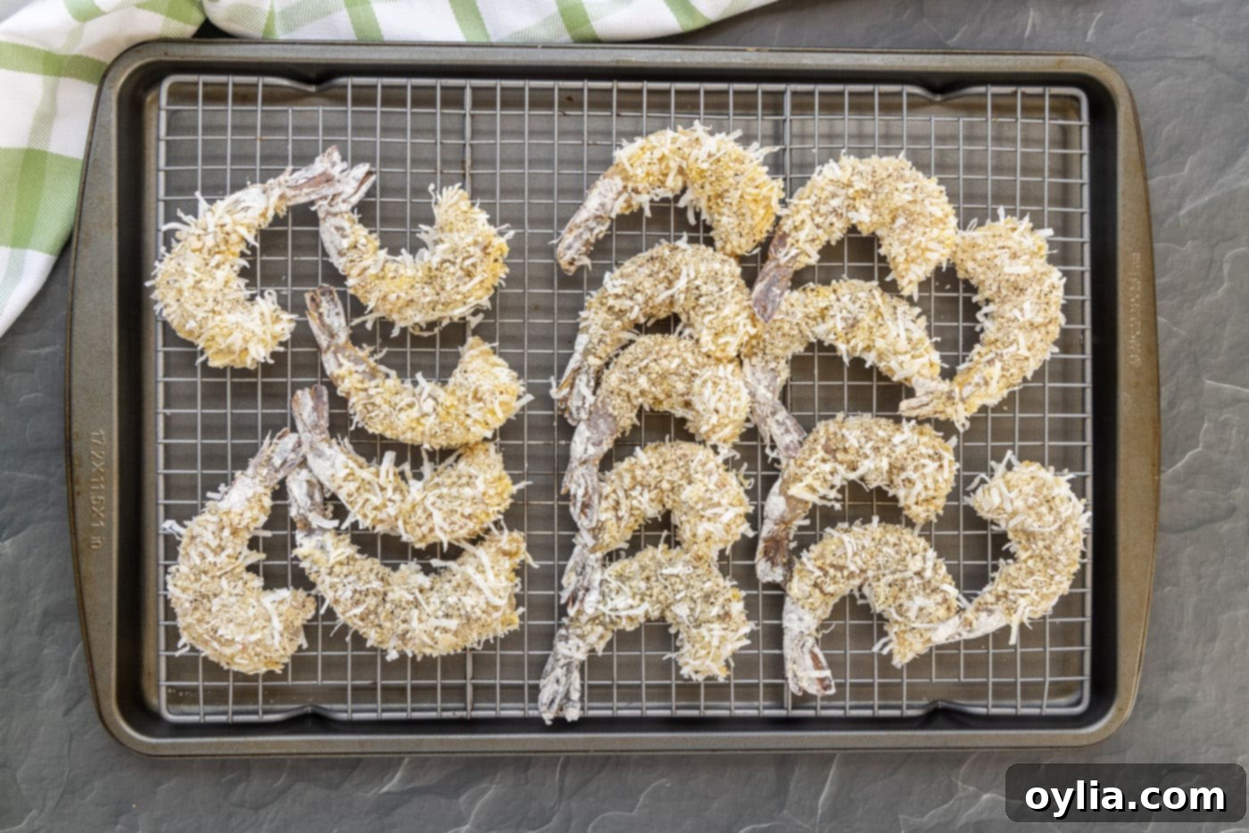Several breaded coconut shrimp resting on a wire baking sheet, ready for the air fryer.