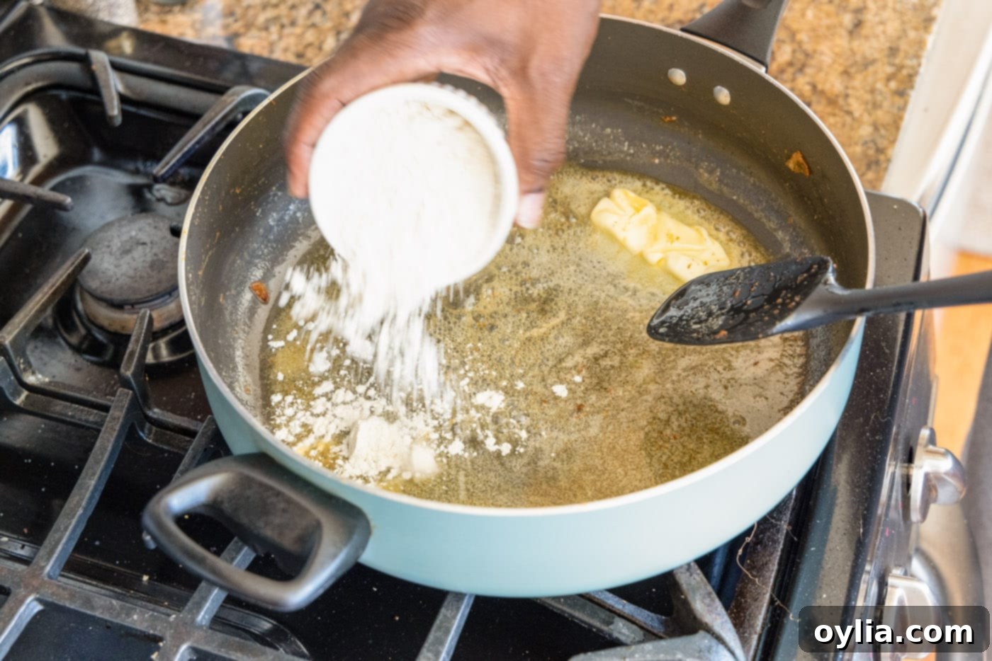 adding flour to make a roux in a skillet