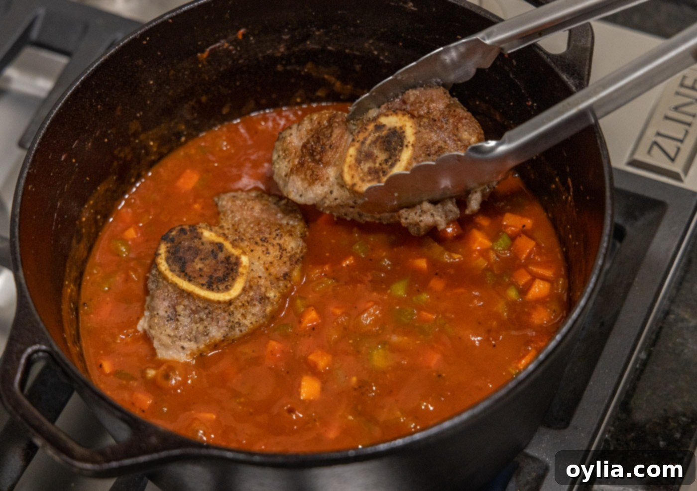 Adding seared veal shanks back into the Dutch oven with braising liquid
