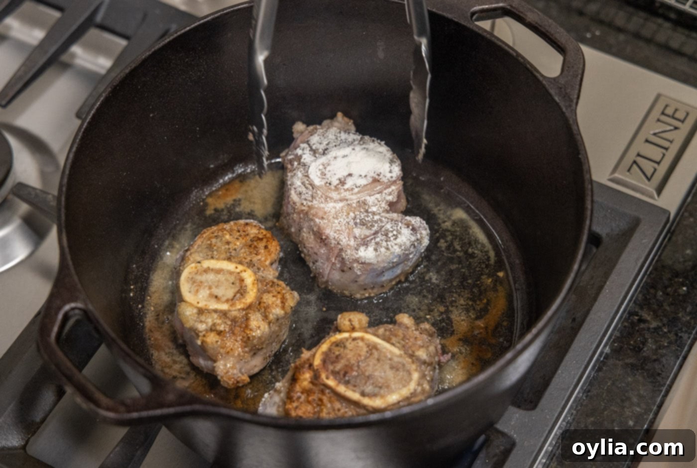 Flipping veal shanks to sear the other side in a hot Dutch oven
