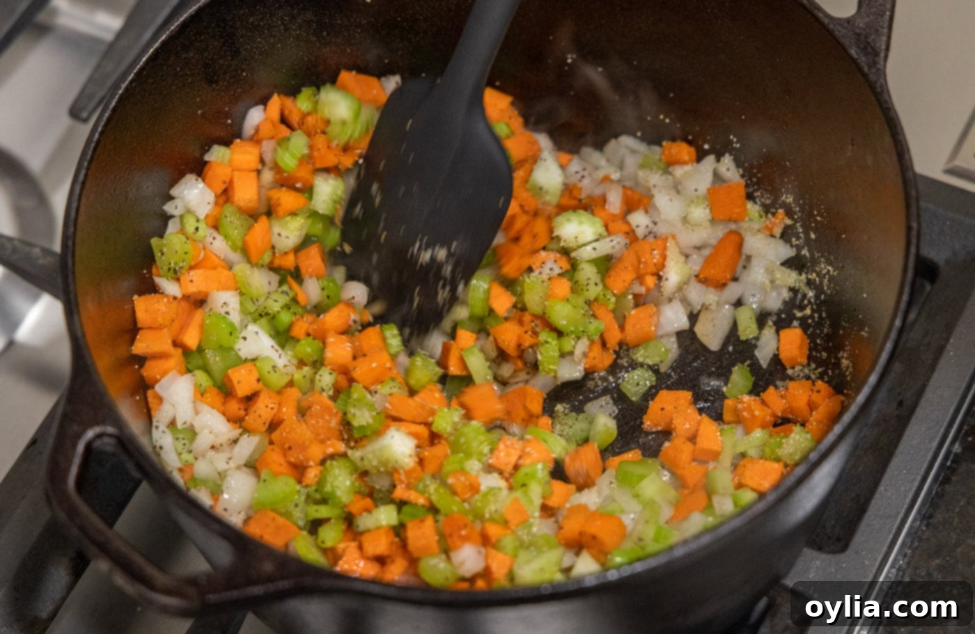 Cooking onion, celery, and carrots in a pan to create the aromatic base