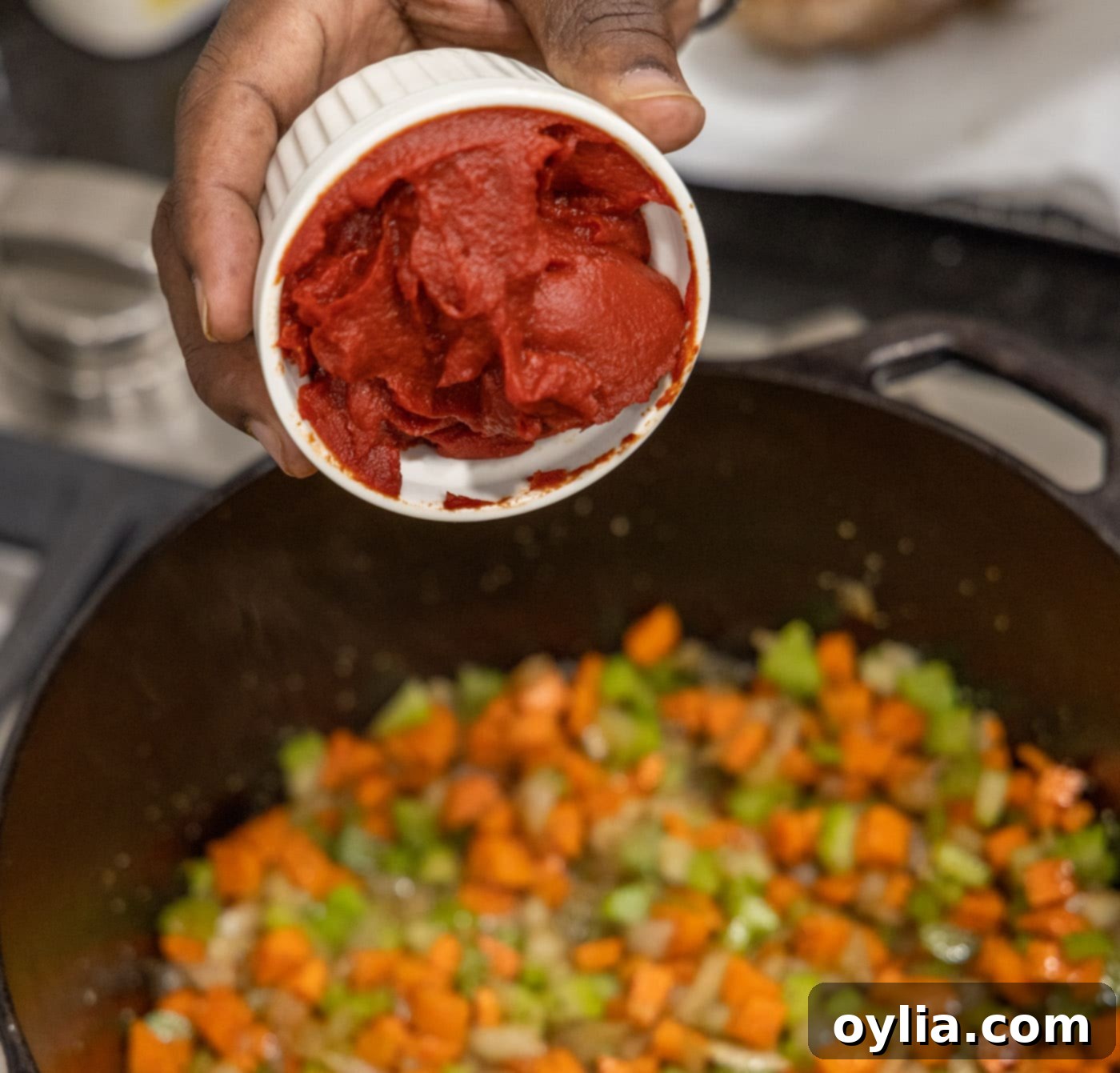 Adding tomato paste to the sautéed celery, onion, and carrots in a Dutch oven