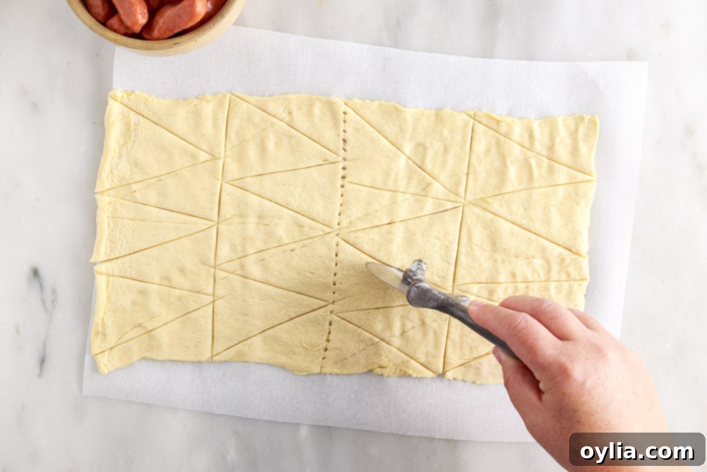 slicing crescent roll dough into triangles with a pizza cutter